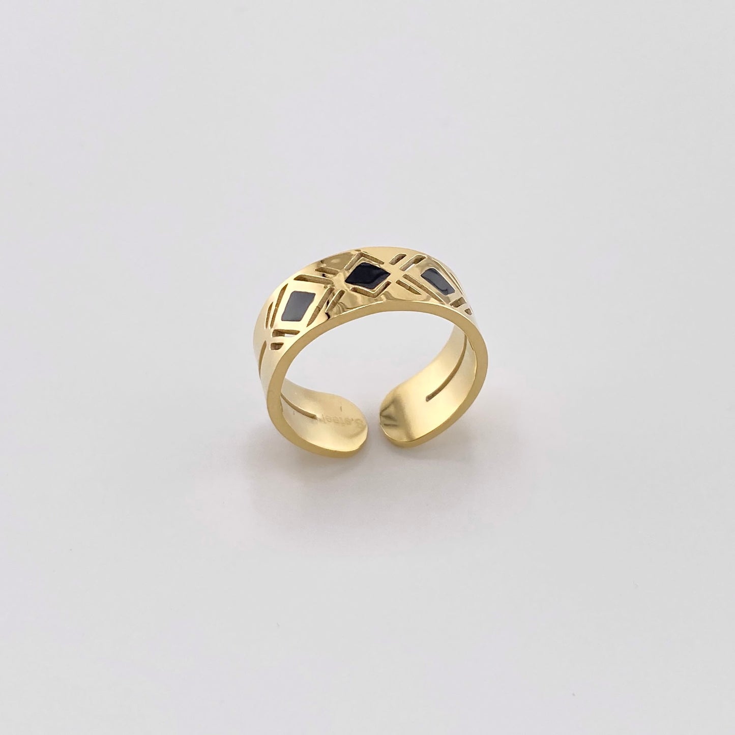 Gold-plated stainless steel ring with a geometric pattern and black enamel, French brand Ikita.