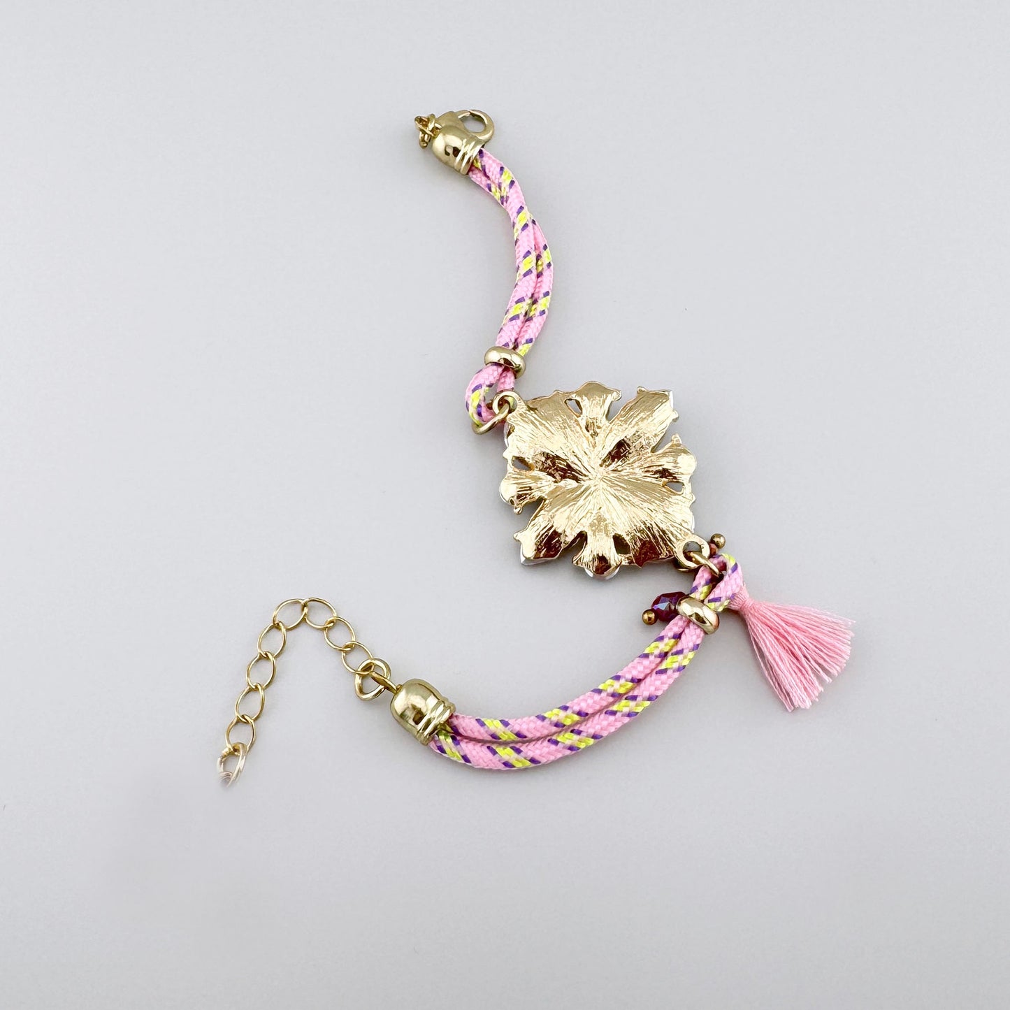 Браслет с плетёным розовым ремешком и кристаллами в форме цветка.