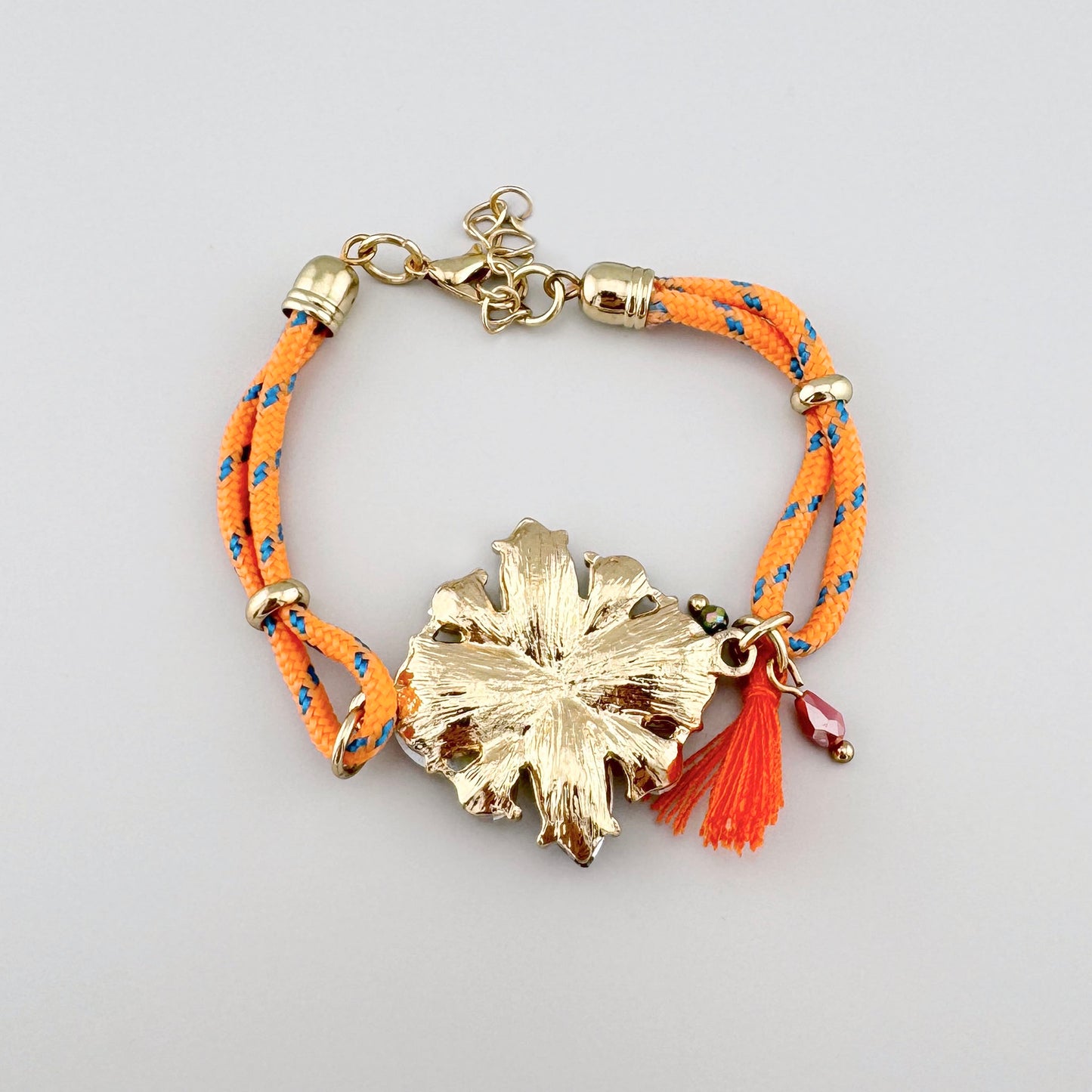 Armband mit orangefarbenem geflochtenem Band und blumenförmigen Kristallen.