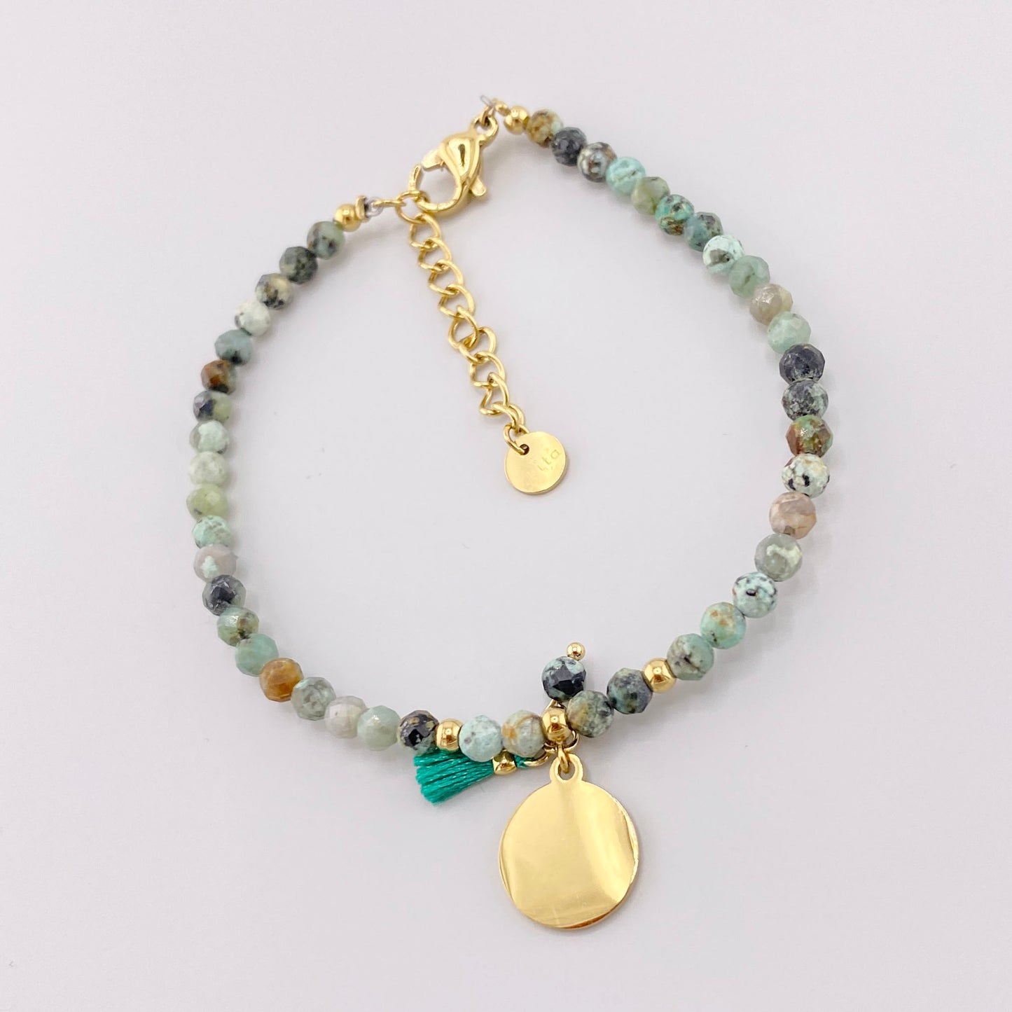 Pulsera con turquesa africana, piedras facetadas, medallón dorado y borla turquesa, marca francesa Ikita.