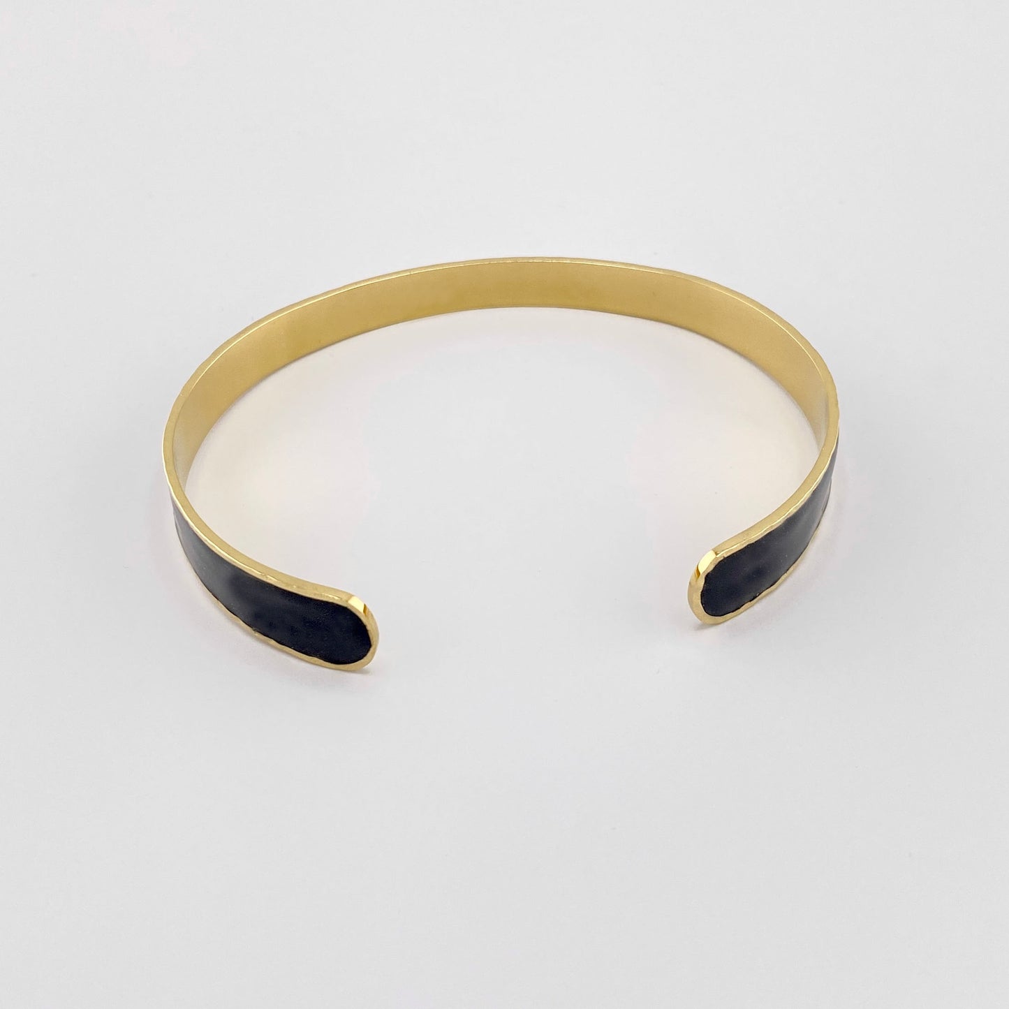 Gold-tone bracelet with black enamel detailing, French brand Ikita.