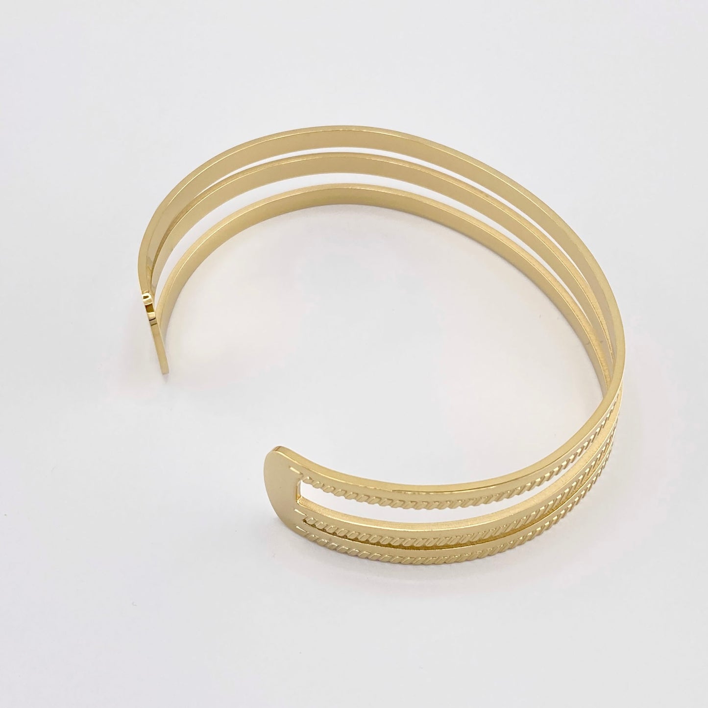 Pulsera abierta de acero dorado con tres finas bandas, marca francesa Ikita.