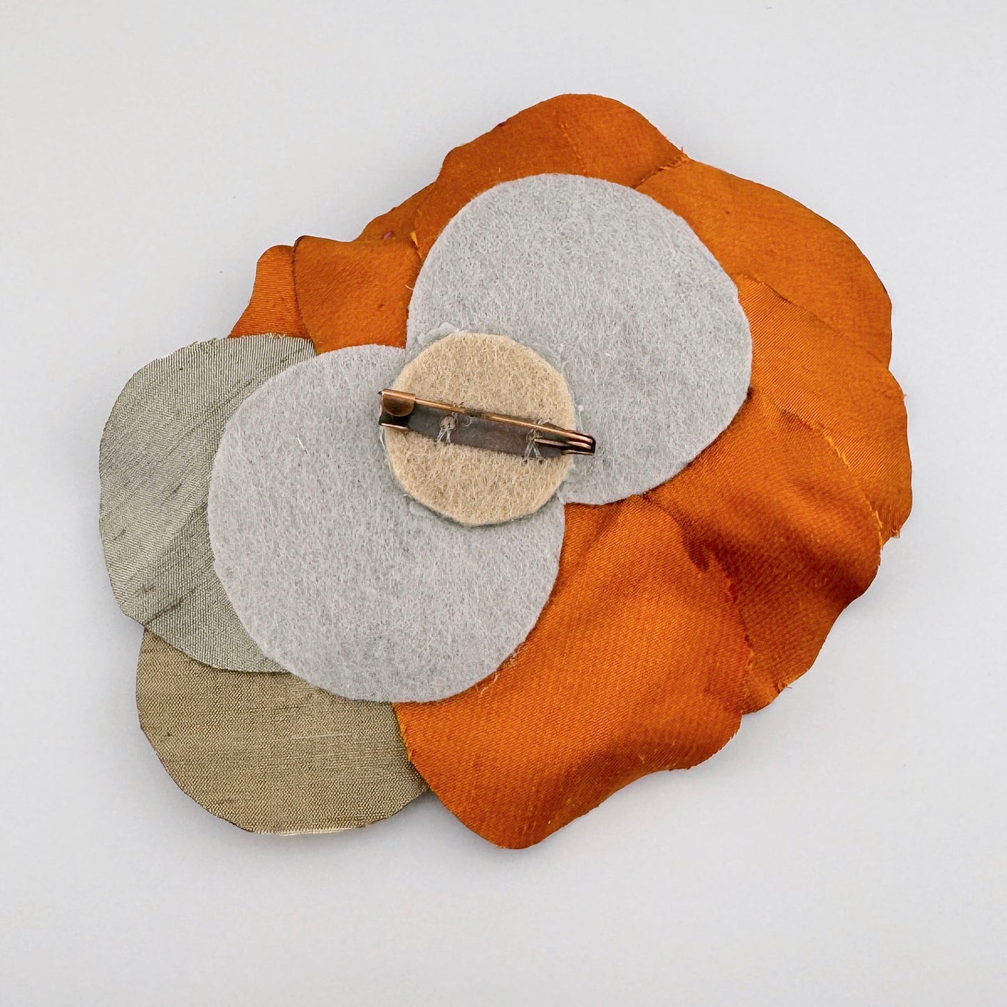 Оранжевая брошка в форме цветка из шелка, украшенная разноцветными бусинами и кристаллами.