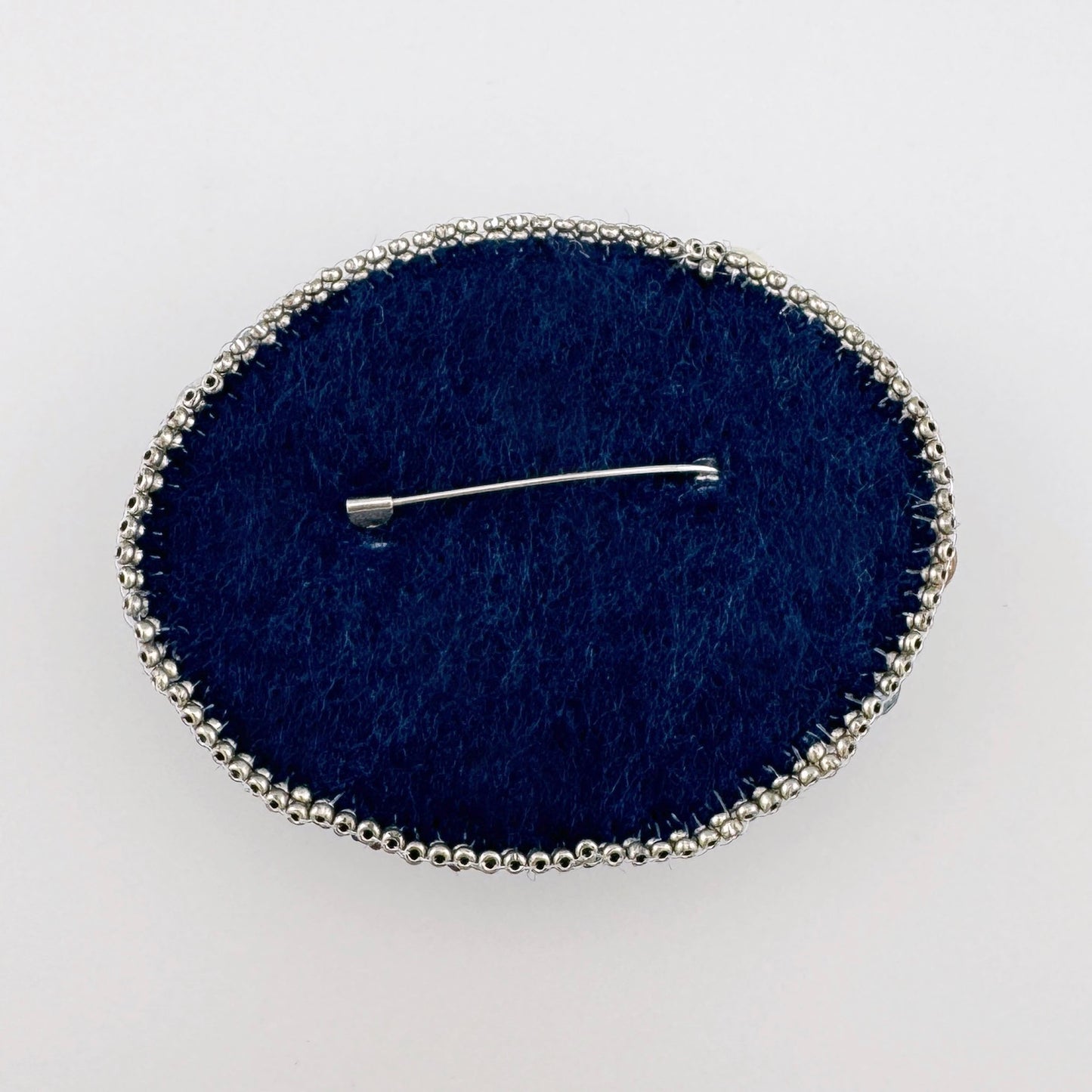 Broche ovalado con cuentas de colores, elaborado a mano con esmero.