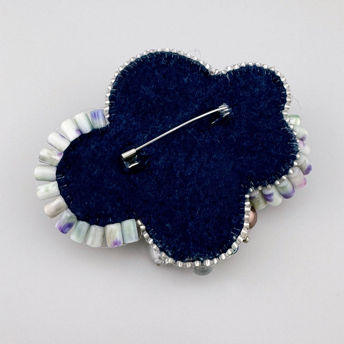 Broche hecho a mano decorado con diversas cuentas y cristales en tonos azul, verde, rosa y blanco perla, marca BroszArt.