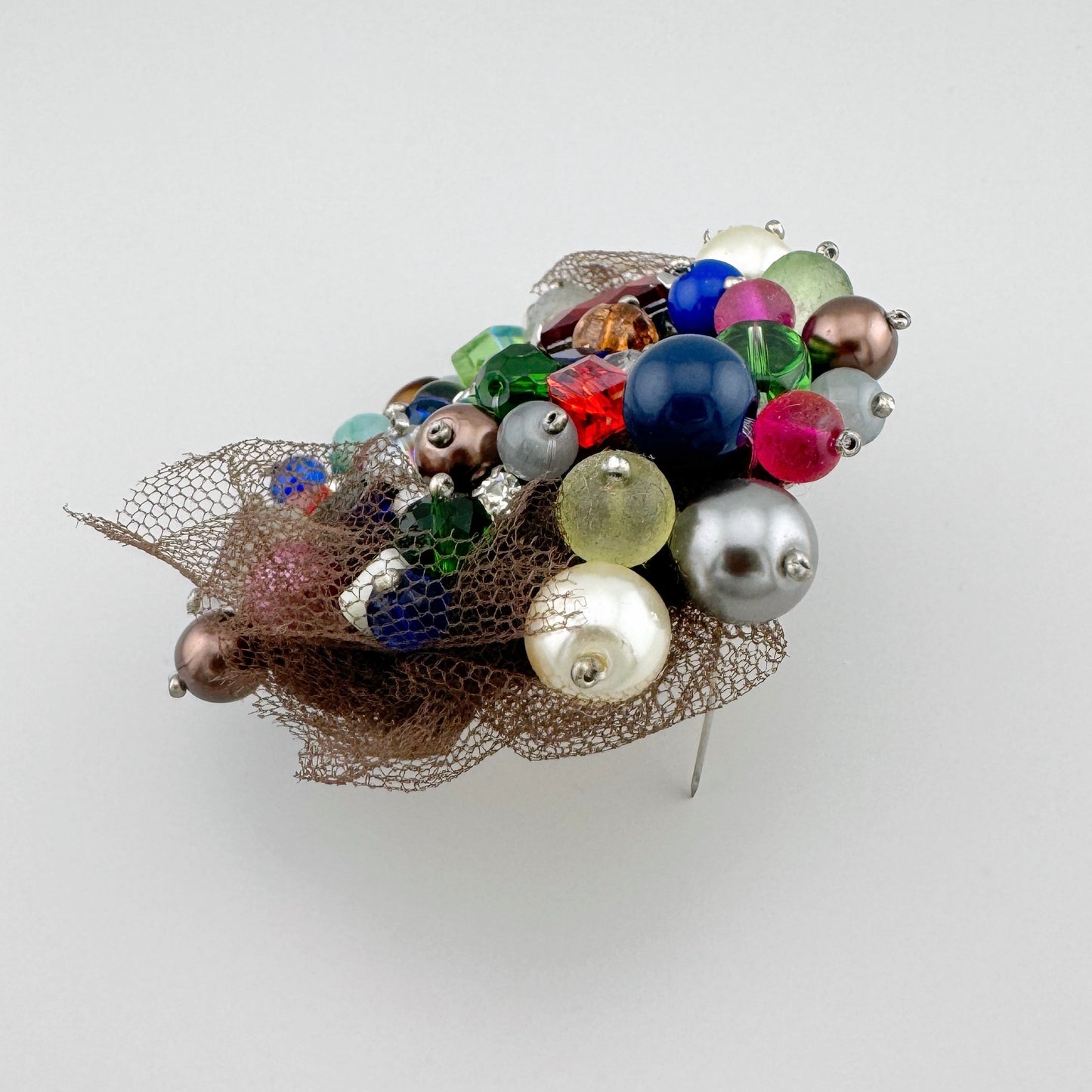 Broche avec perles multicolores, ornée d'un filet brun.