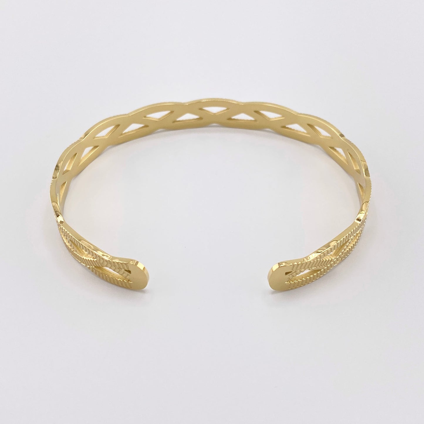 Gold-plated openwork bracelet with braid-shaped cutouts, French brand Ikita.