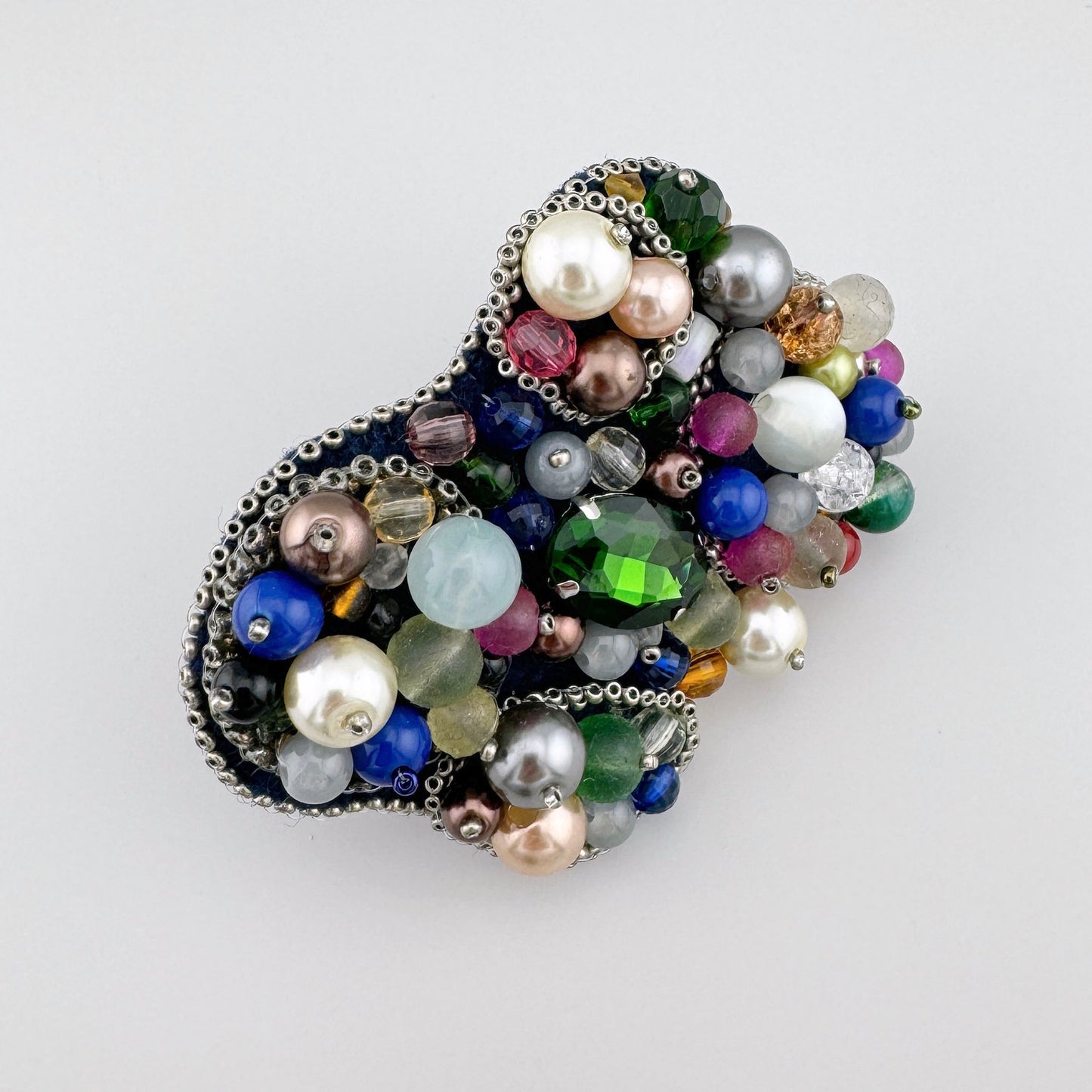 Broche hecho a mano adornado con cuentas multicolores y un gran cristal verde, marca polaca BroszArt.