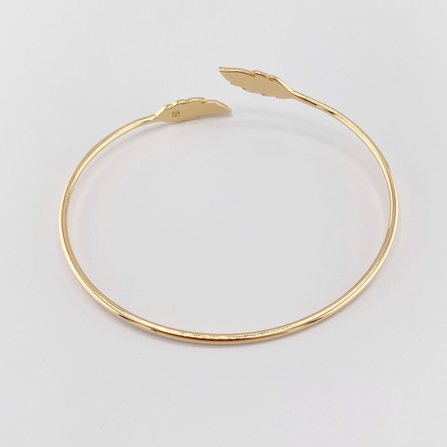 Pulsera rígida bañada en oro con diseño abierto y detalles de hojas en ambos extremos, marca francesa IRL.