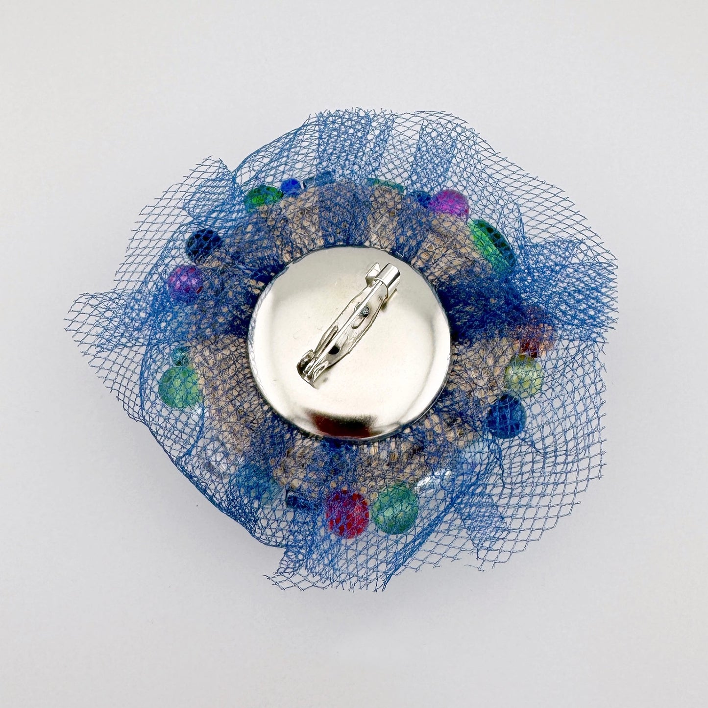 Broche único hecho a mano con cuentas multicolores sobre una malla azul, marca polaca BroszArt.