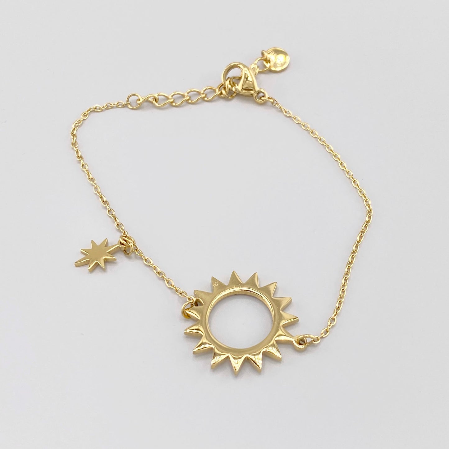 Gold-plated bracelet with a sun-shaped pendant adorned with zircons and a small star, French brand Ikita.