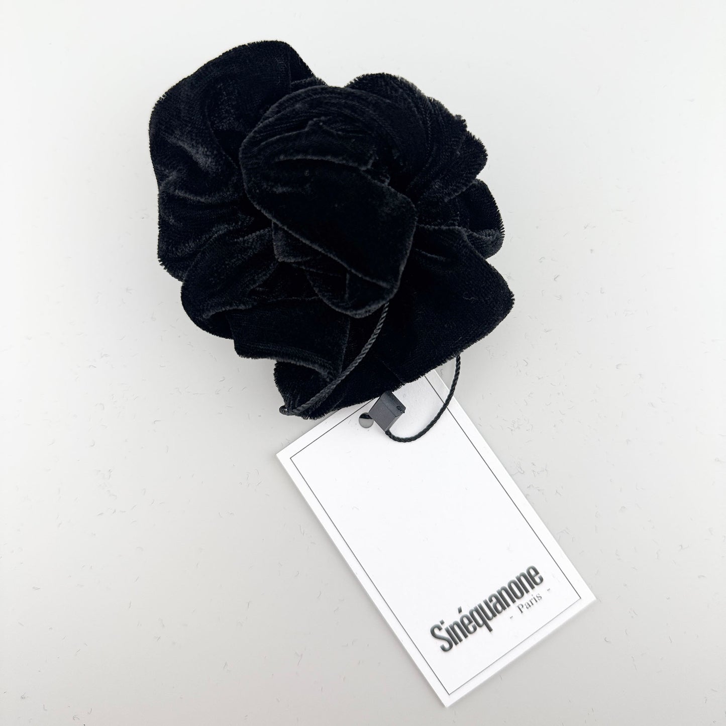 Schwarzer Samt-Scrunchie von Sinequanone Paris mit sichtbarem Markenetikett