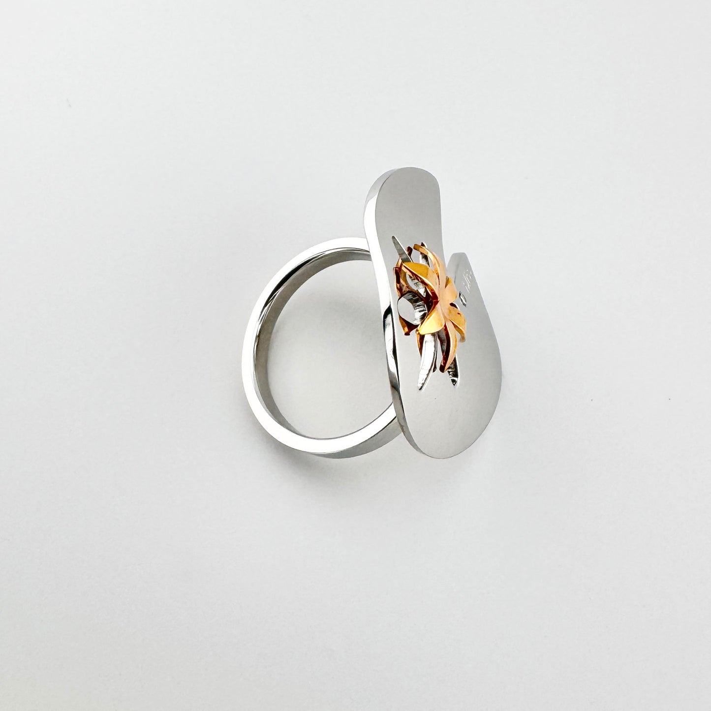 Anillo con flor calada, perfil limpio y detalle bicolor elegante