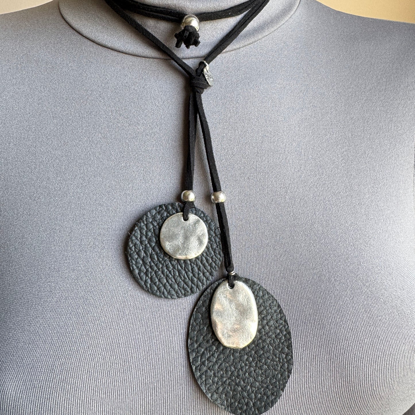 Black boho necklace with leather and silver-tone pendants styled on outfit
