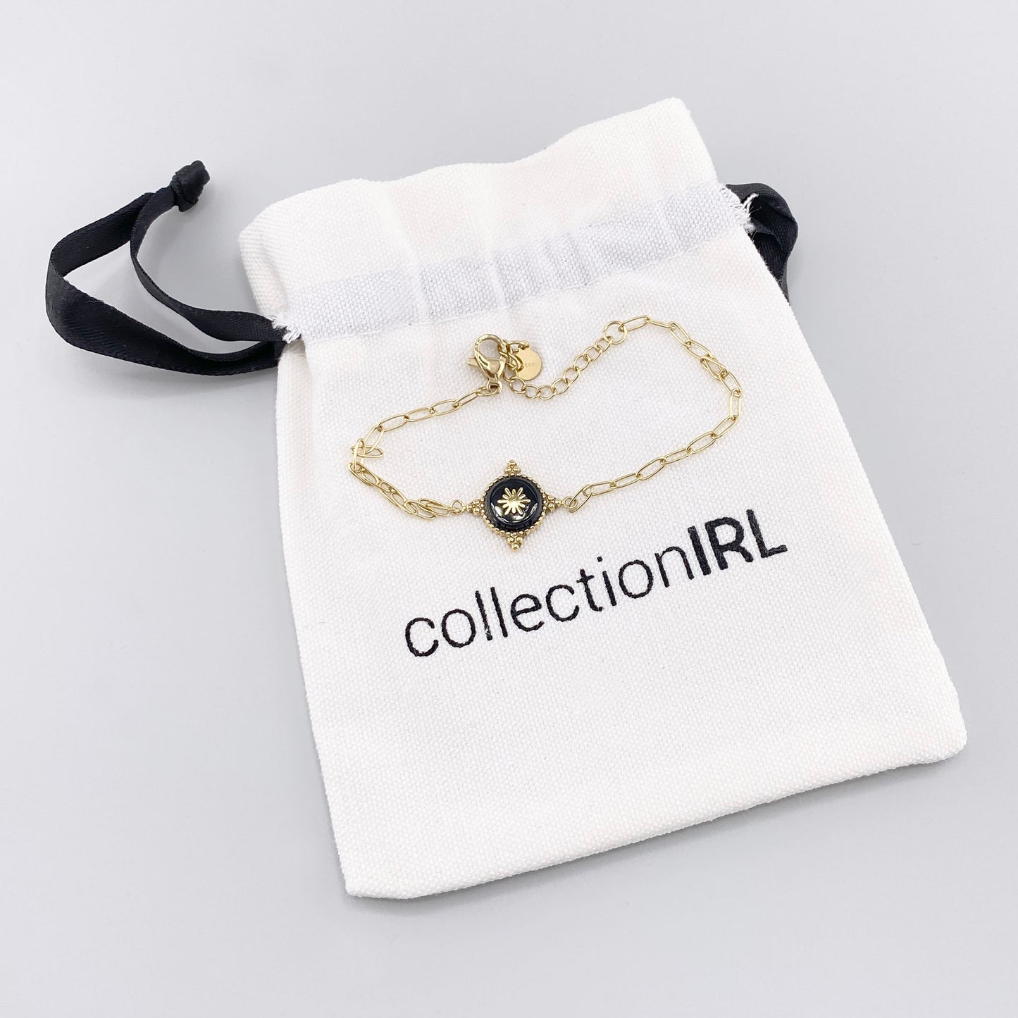 Bracelet doré avec médaille noire dans pochette de marque