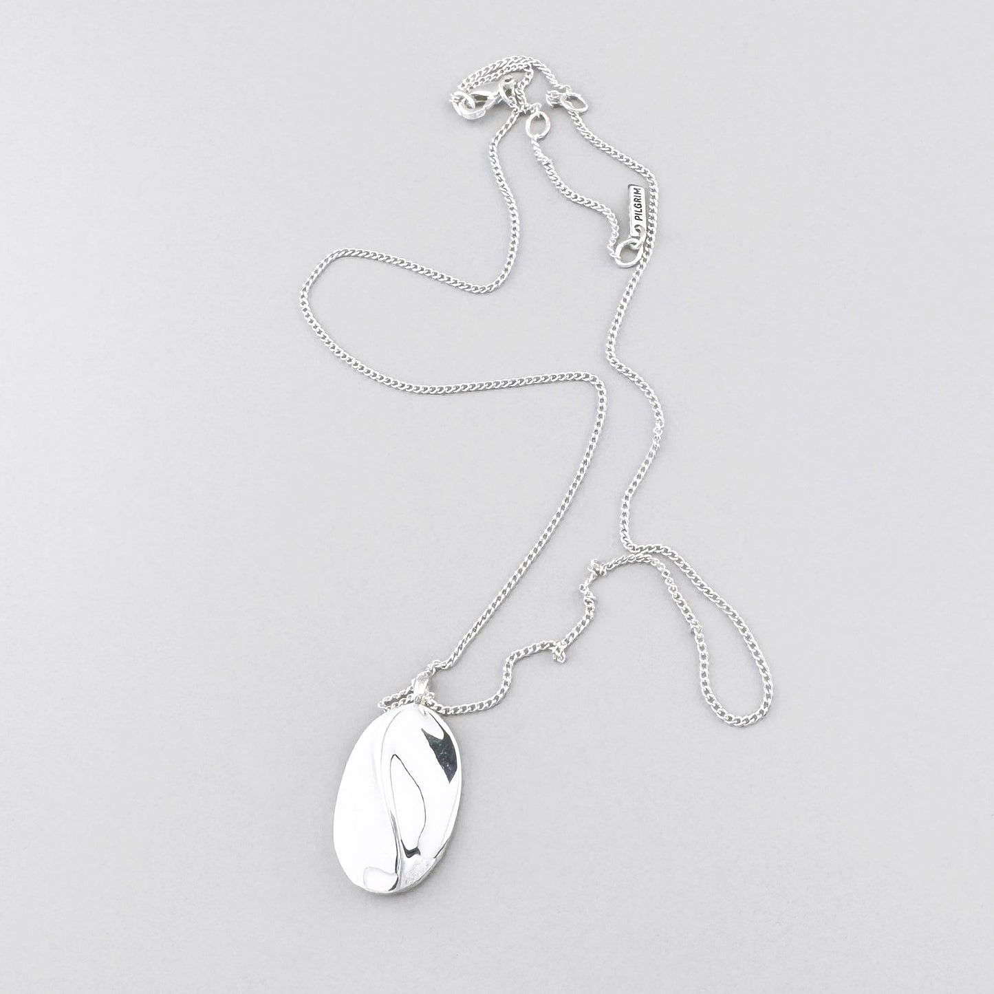 Feine Halskette mit ovalem Anhänger und glänzender Oberfläche im minimalistischen Stil