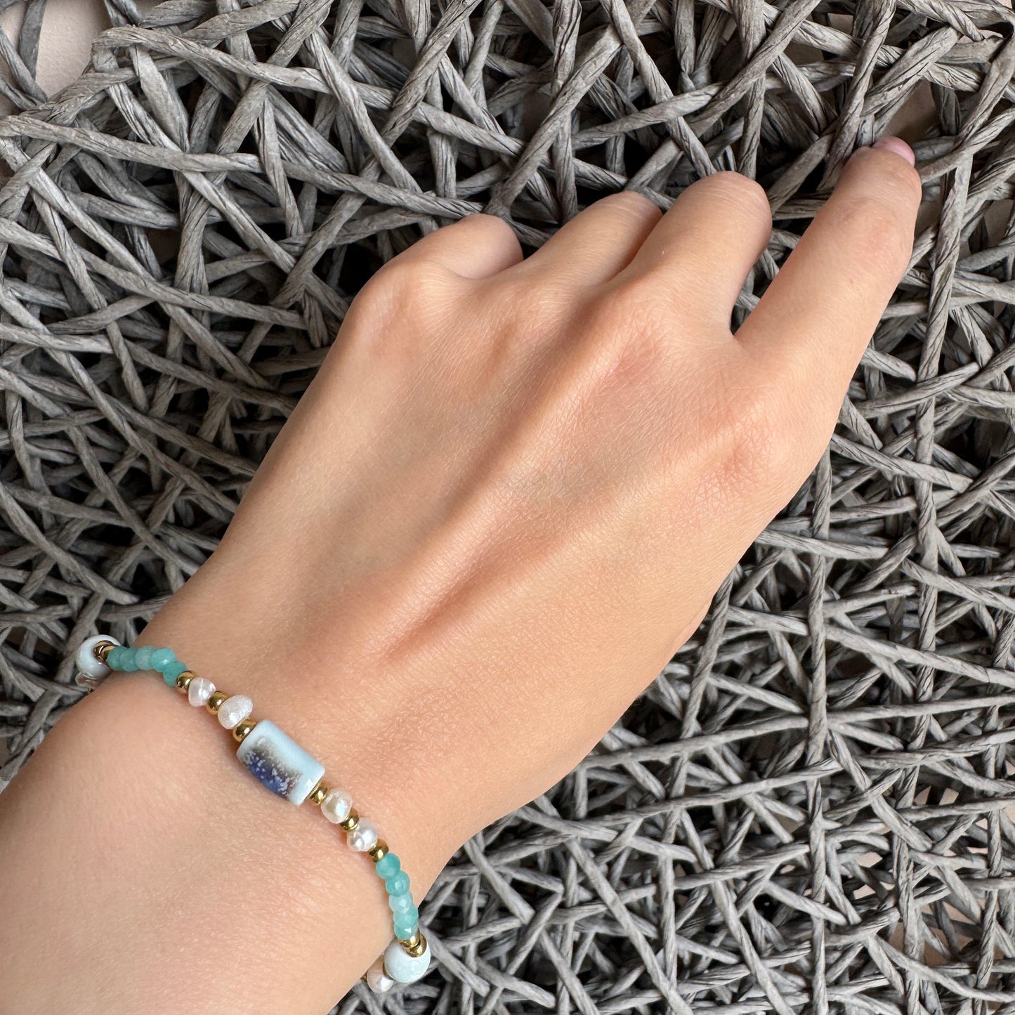 Delicate amazonite and pearl bracelet with golden accents worn on wrist