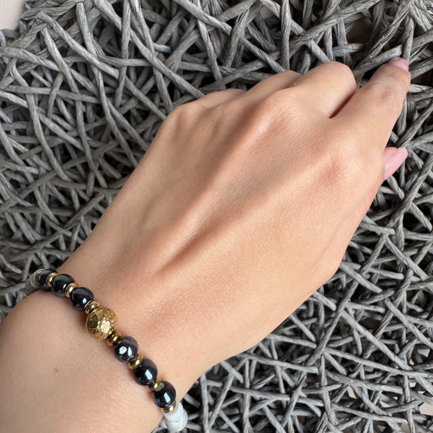 Elegant bracelet with pearl and graphite beads worn on wrist with golden accents