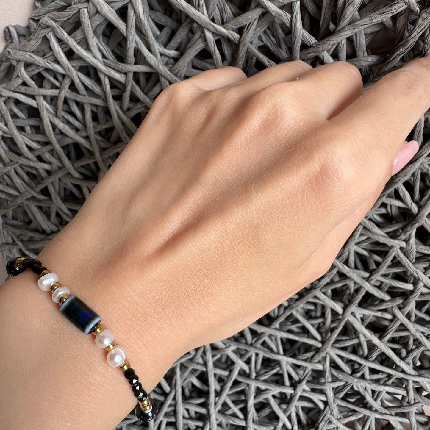 Elegant bracelet with black spinel and pearls worn on wrist with gold accents
