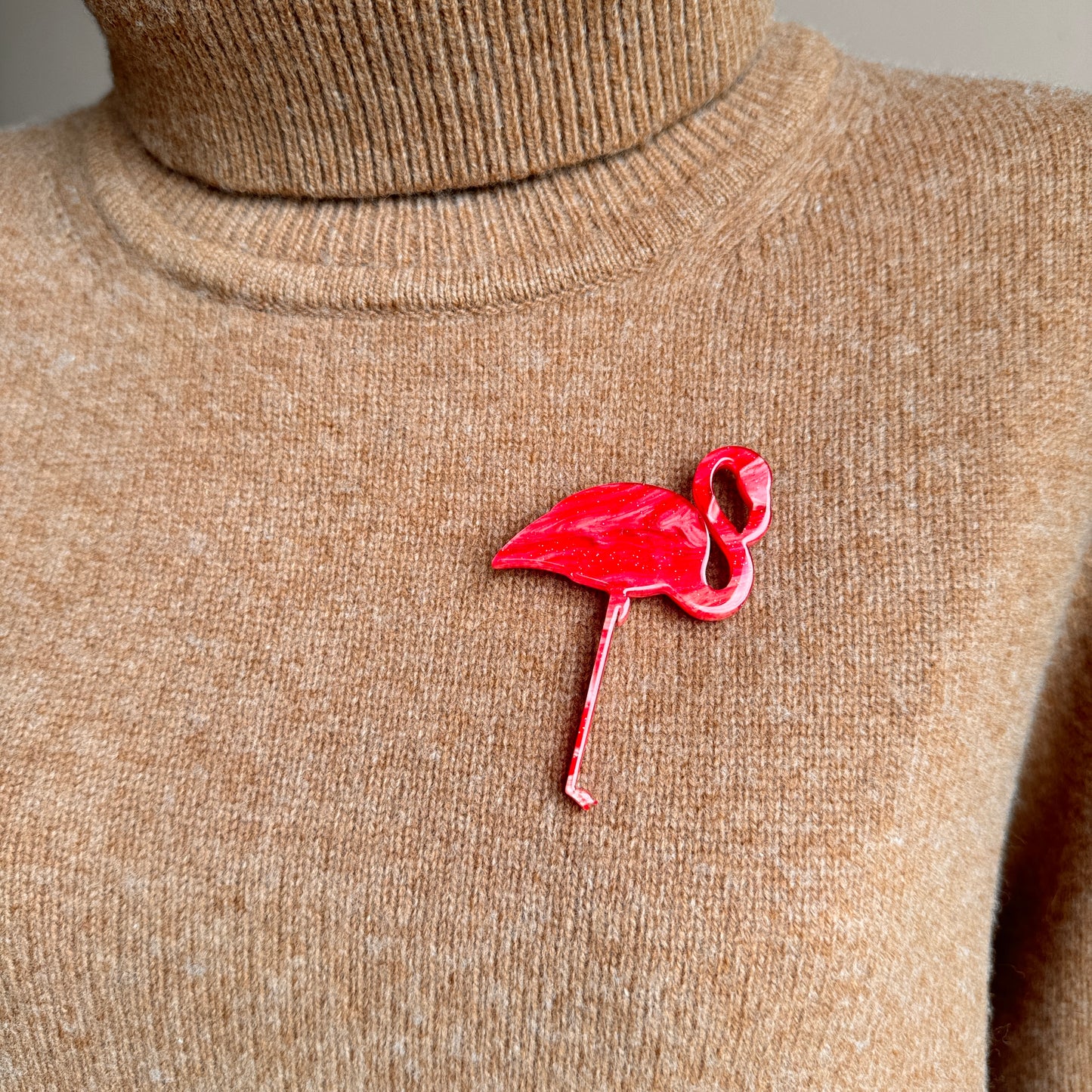 Crimson flamingo brooch on beige sweater in retro pop-art style
