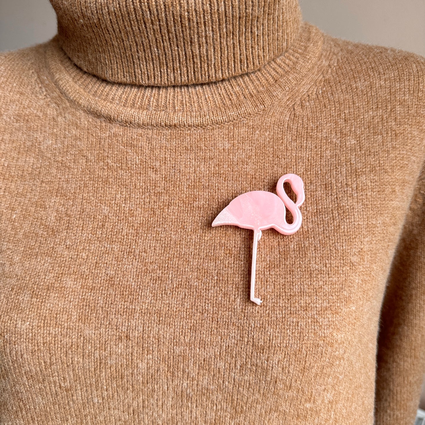 Light pink flamingo brooch worn on beige knitwear