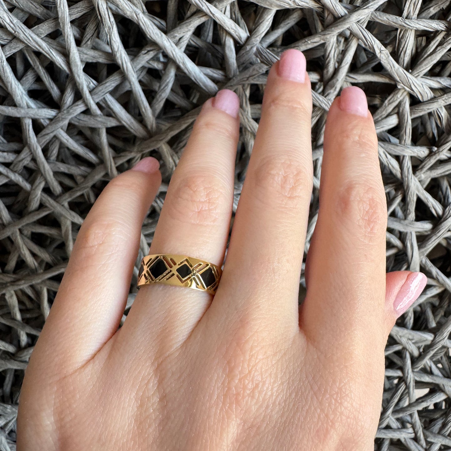 Gold-plated IRL ring with black enamel geometric design on a woman's hand