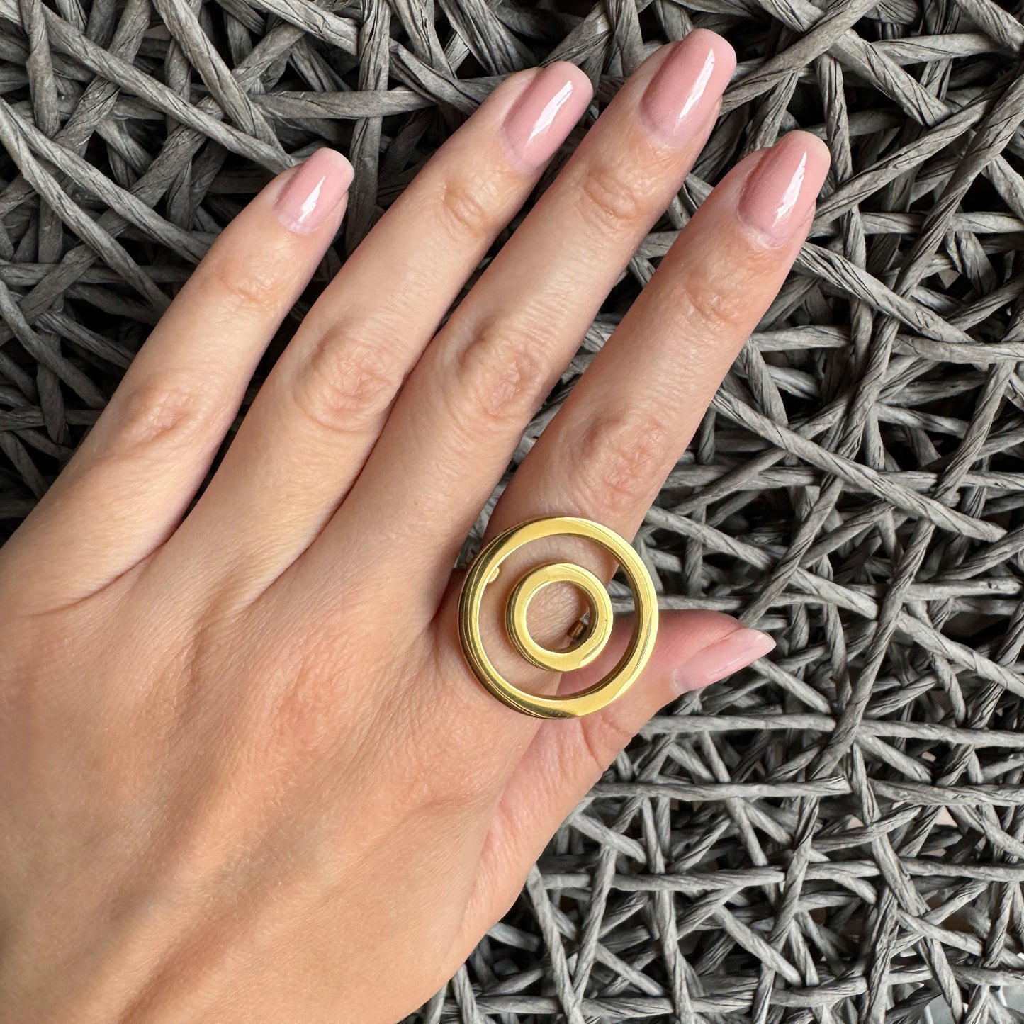 Sculptural gold ring worn on hand featuring modern circular geometry