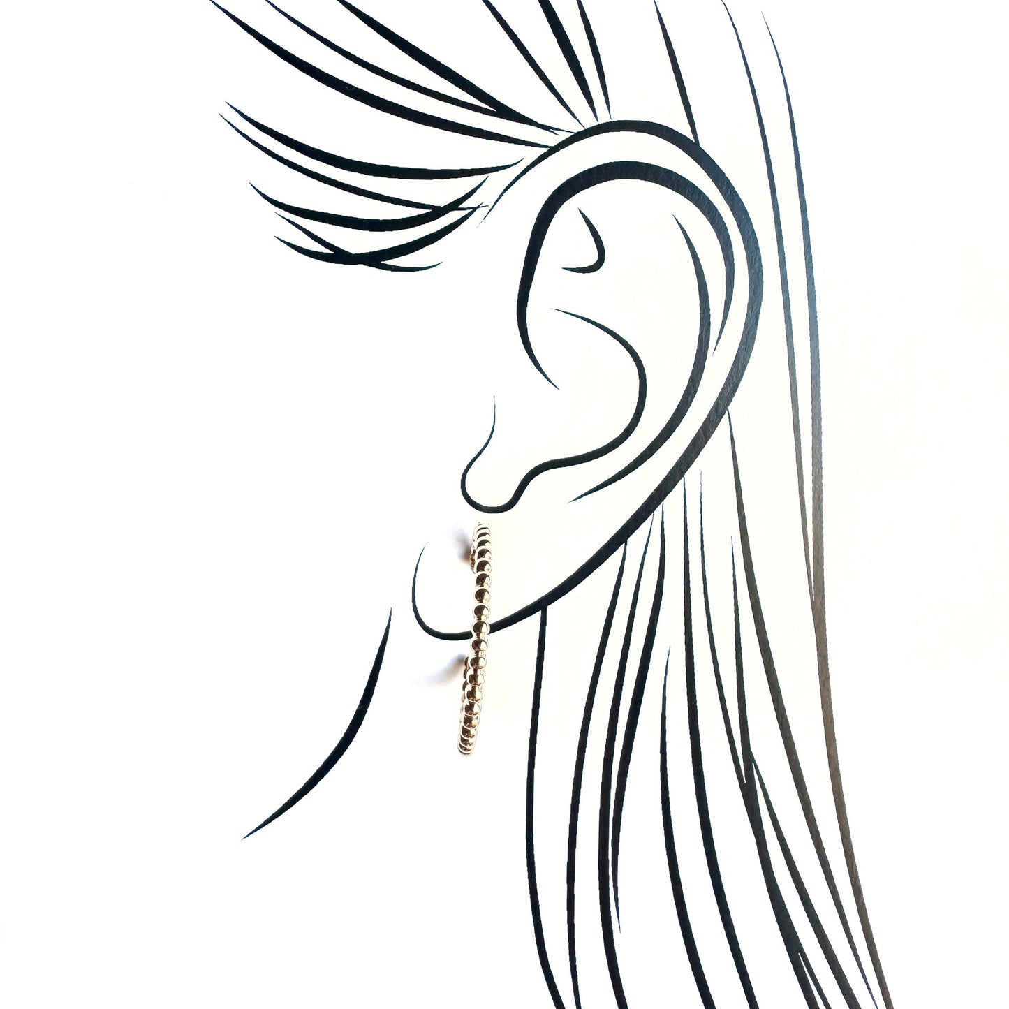 Delicate gold hoop earrings illustrated on an ear silhouette