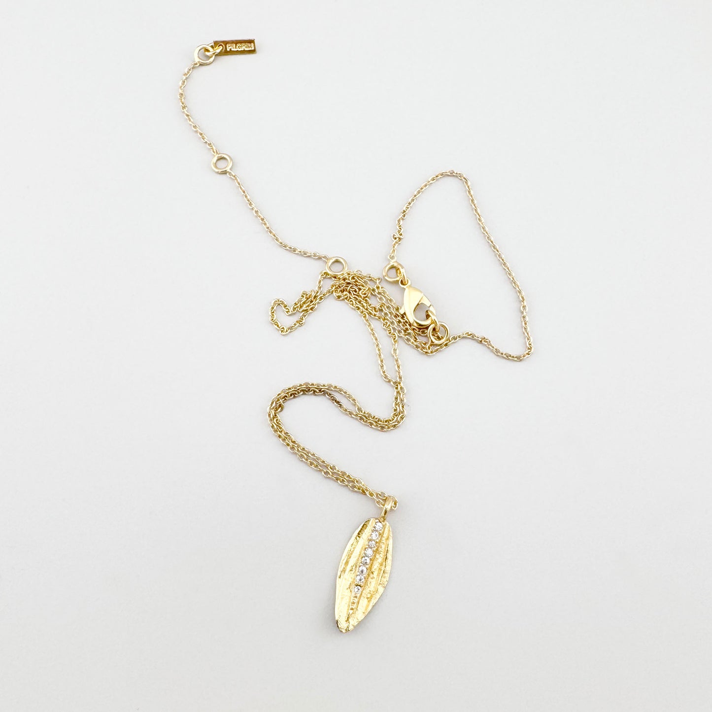 Collier Pilgrim doré avec feuille et zircones présenté sur fond clair