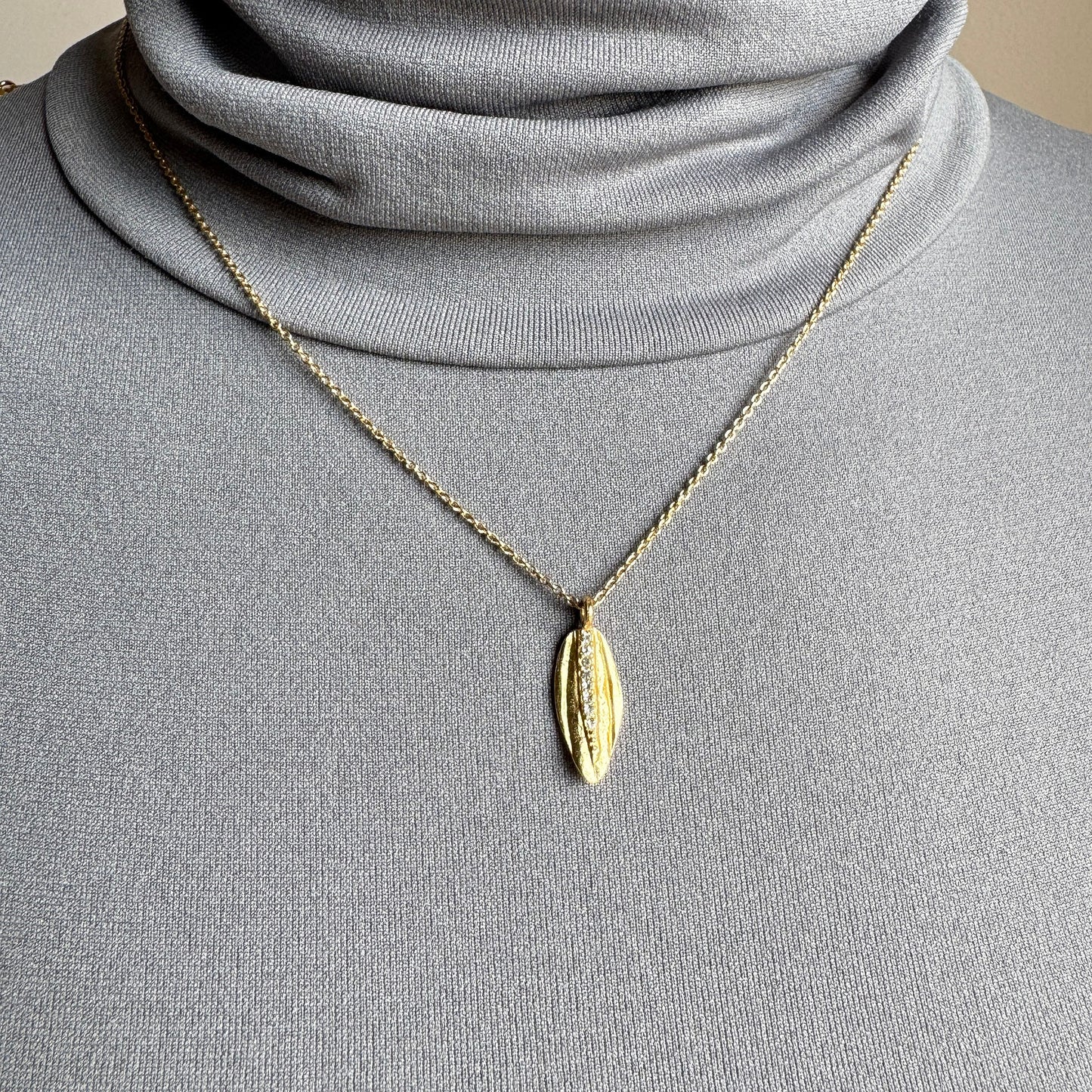 Gold Pilgrim necklace with leaf pendant and zircons worn on neck