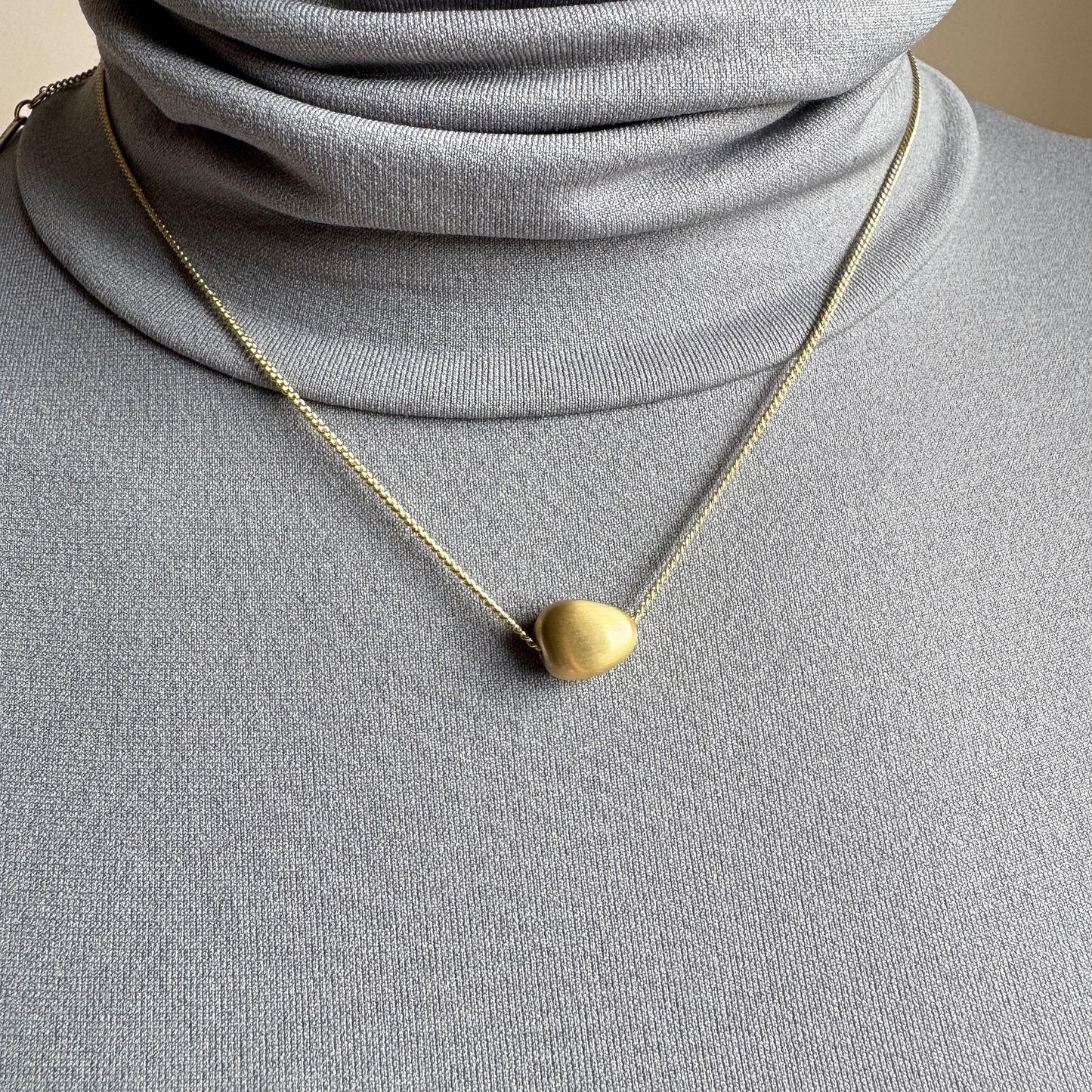Gold Pilgrim necklace with soft matte pendant worn elegantly on neck