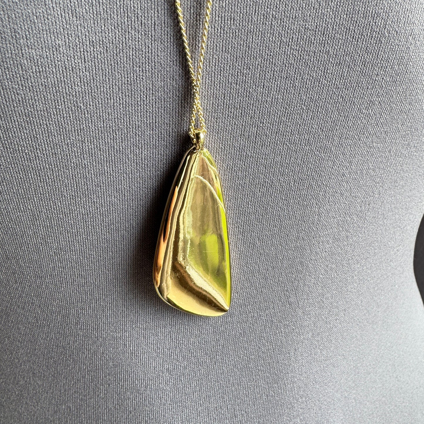 Collier Pilgrim doré avec pendentif large disposé sur fond clair