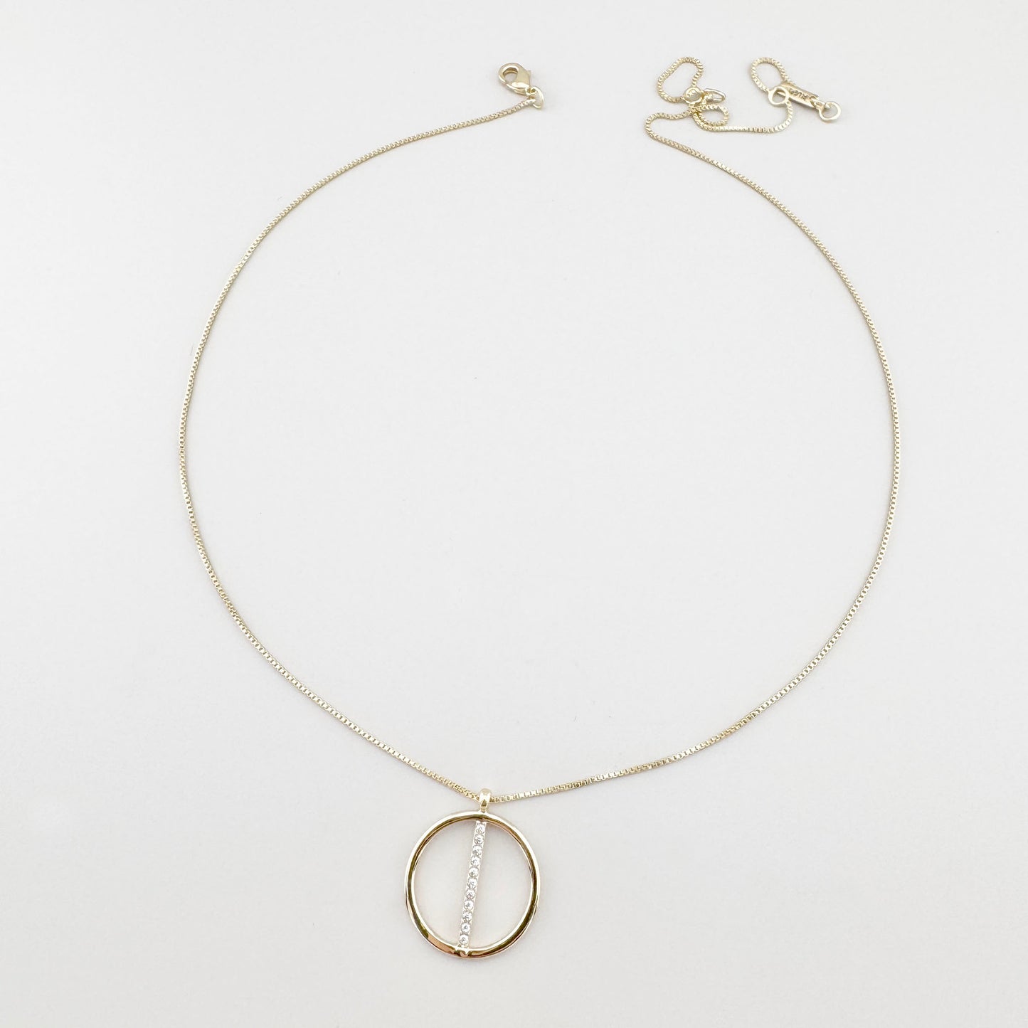 Collier Pilgrim doré avec pendentif rond et zirconias disposé sur fond clair