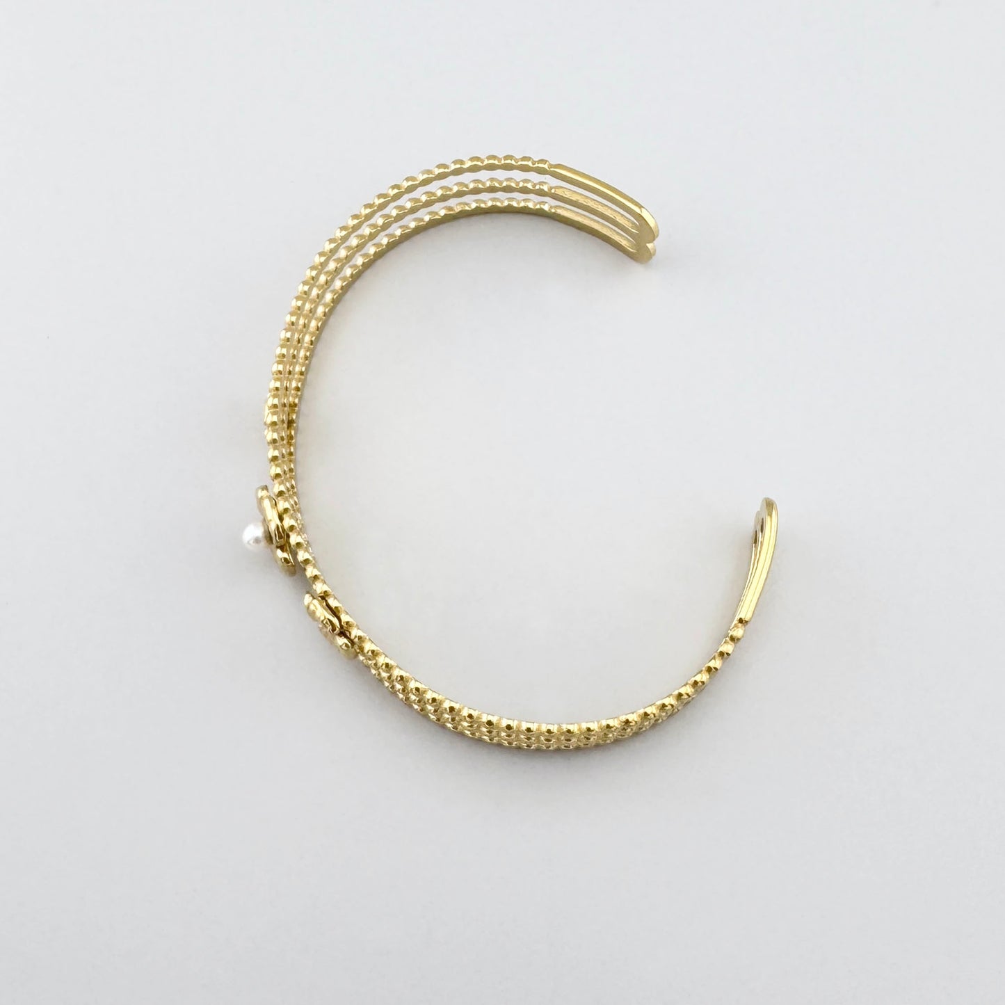 Bracelet manchette doré ajouré avec perle et fleurs stylisées vu de dessus