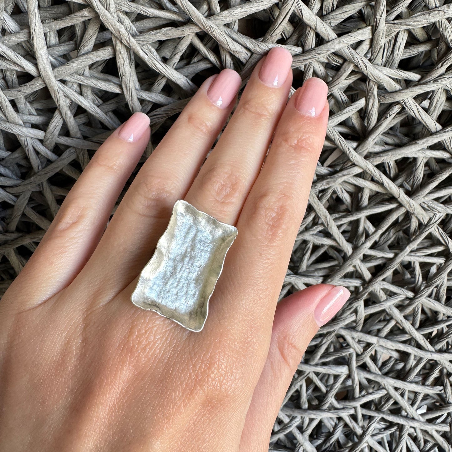 Rectangular silver ring with patina worn on finger with textured edges