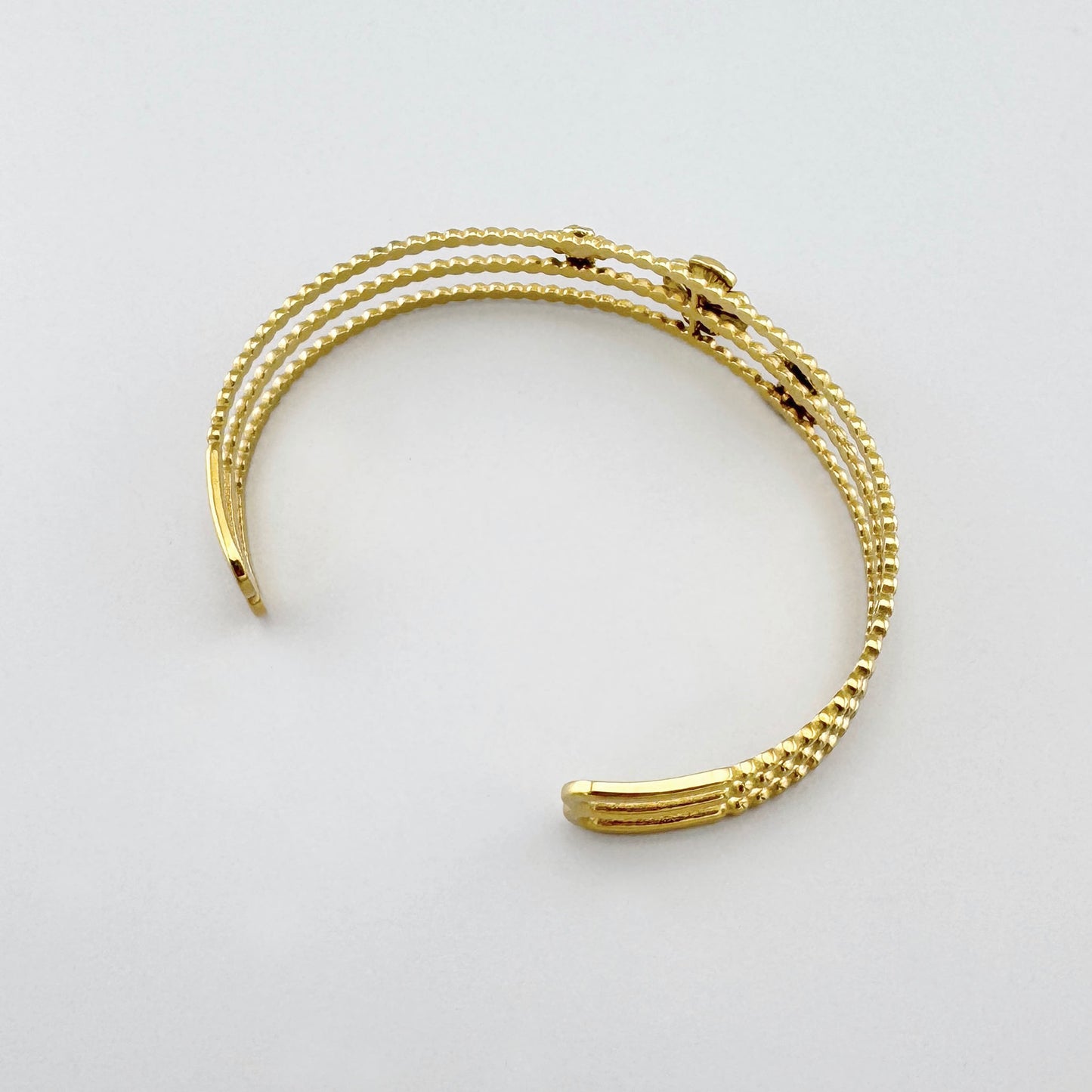 Offene goldene Armspange mit Blumenmuster und Perle in Rückansicht