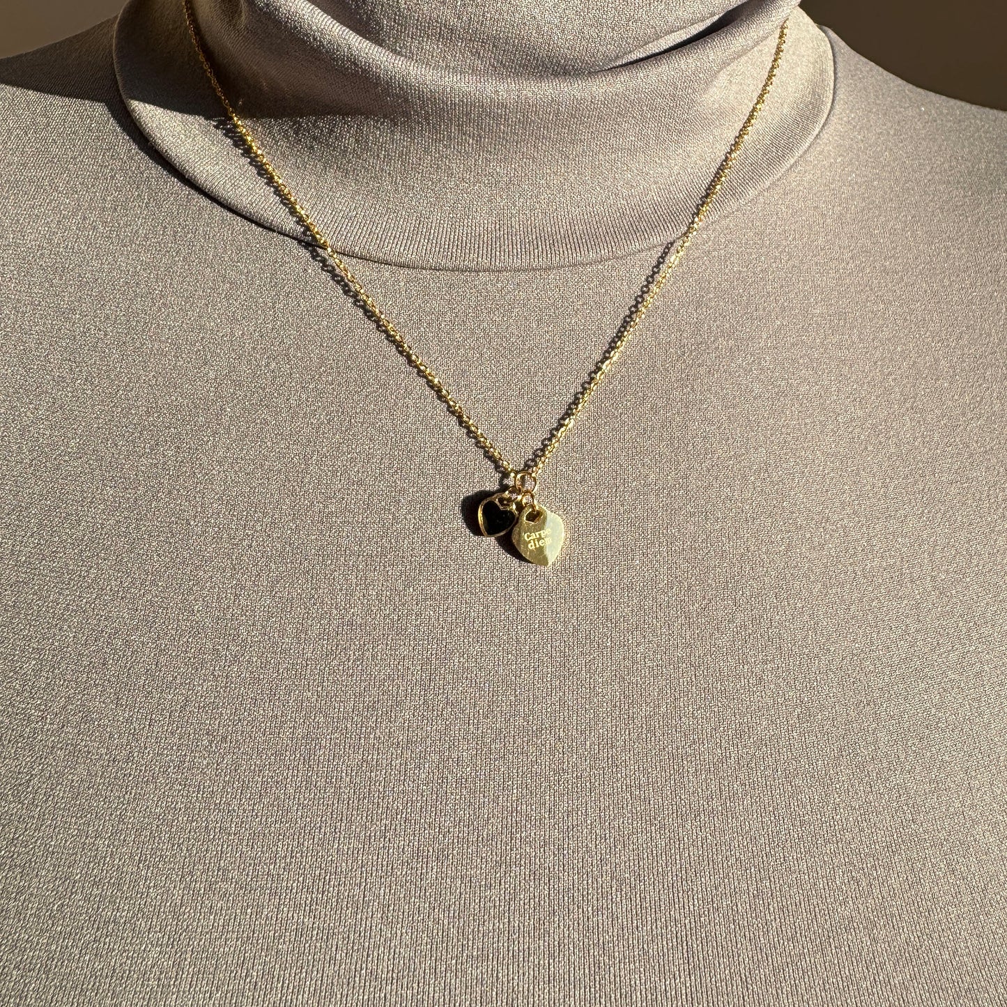 Ikita gold necklace with two heart pendants styled on a mannequin bust
