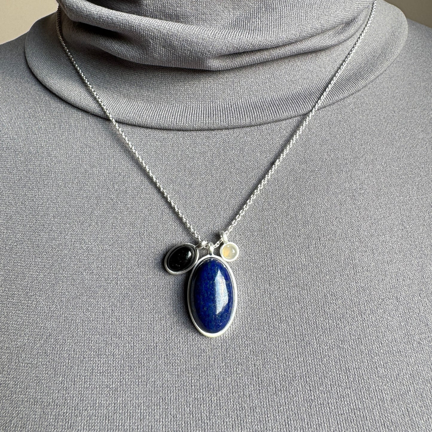 Pilgrim necklace with lapis lazuli, black agate and grey quartz on a silver chain shown on neck