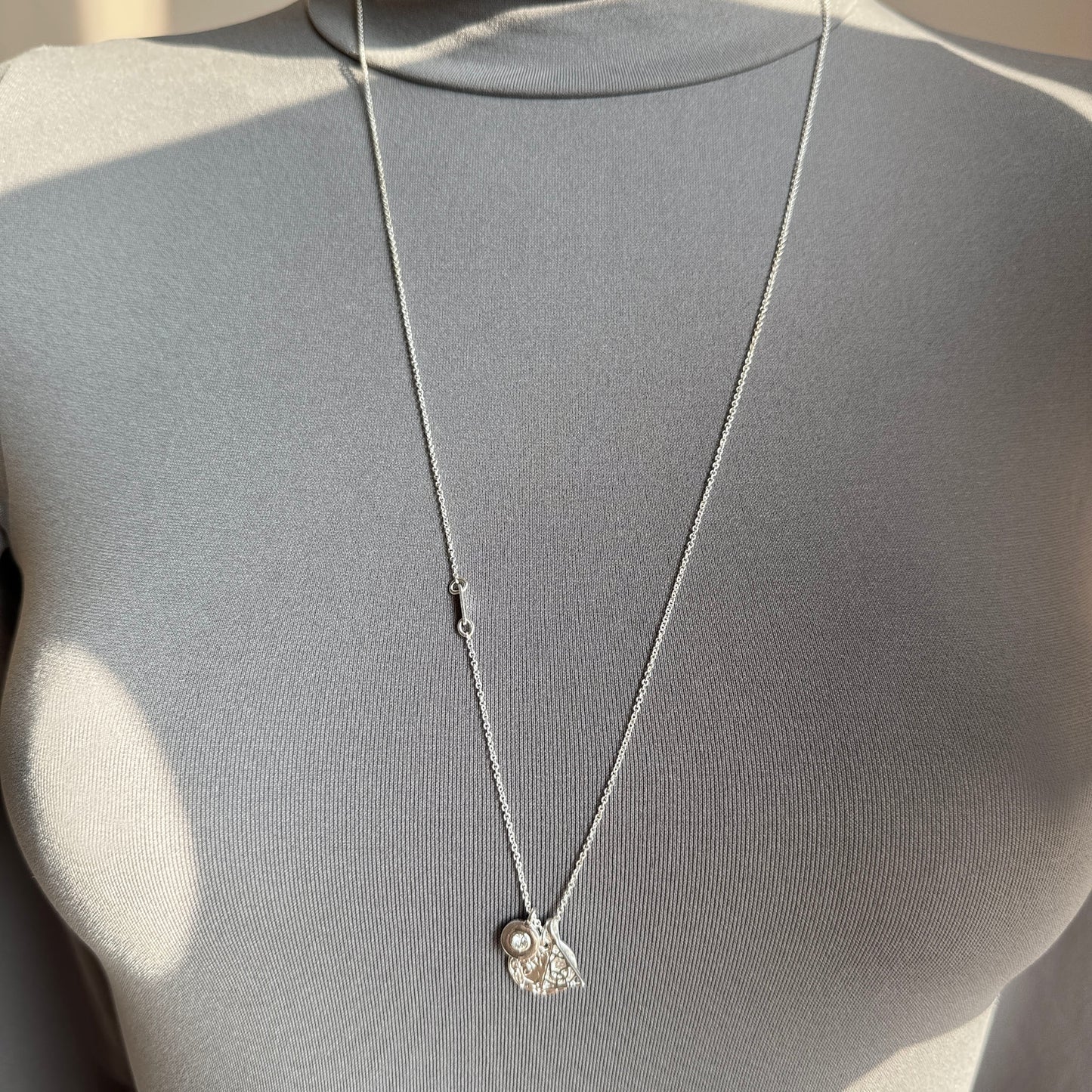Long silver-tone Pilgrim necklace with tree of life, crystal and geometric charm worn on neck