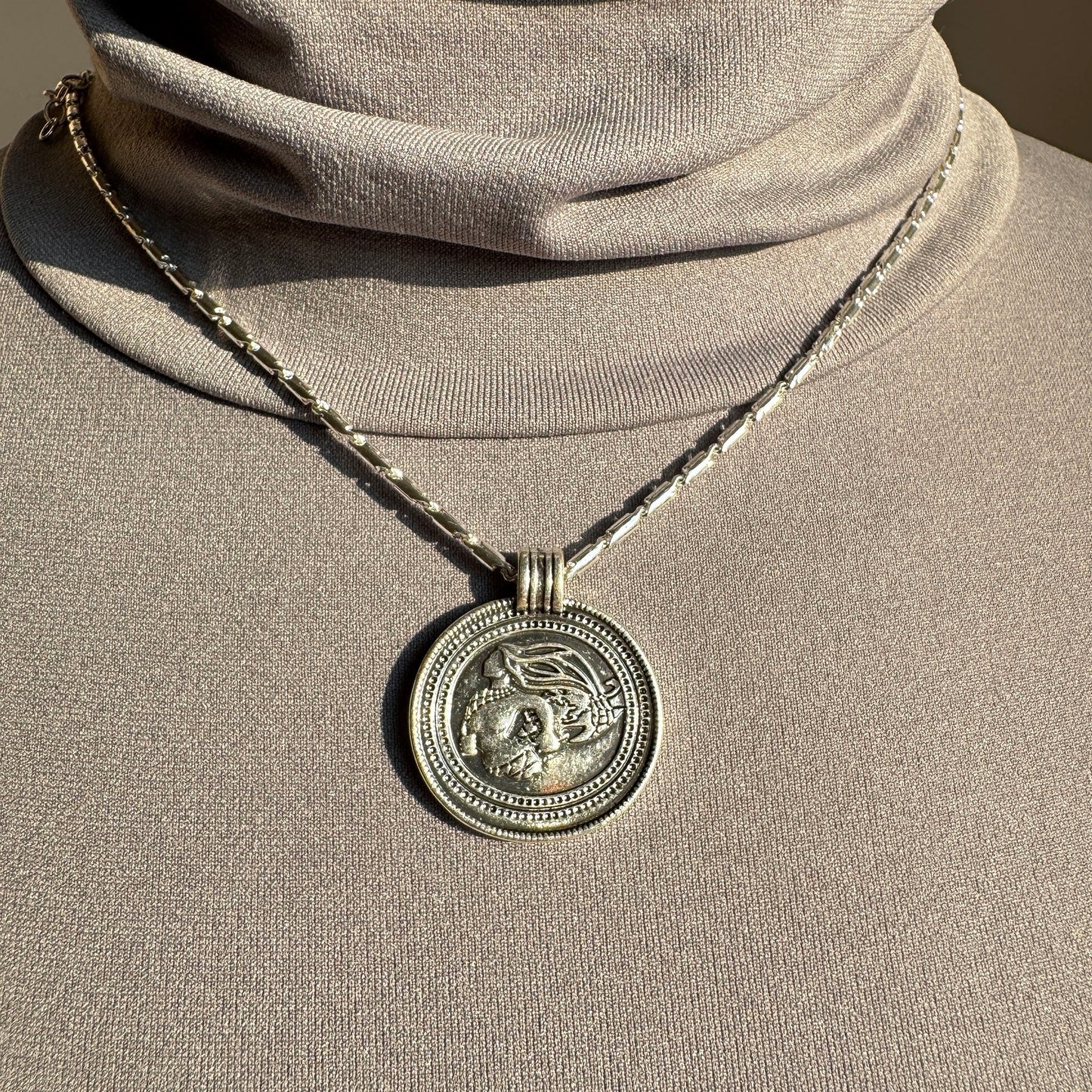 Pilgrim medallion necklace with geometric chain detail worn elegantly on neck