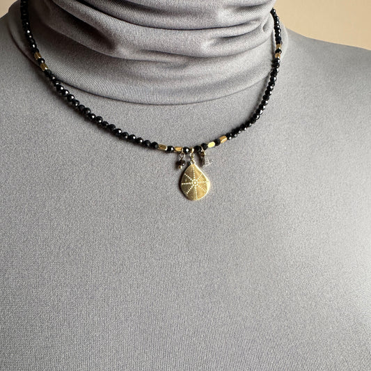 Black stone necklace IRL worn close to the neck with a gold medallion pendant