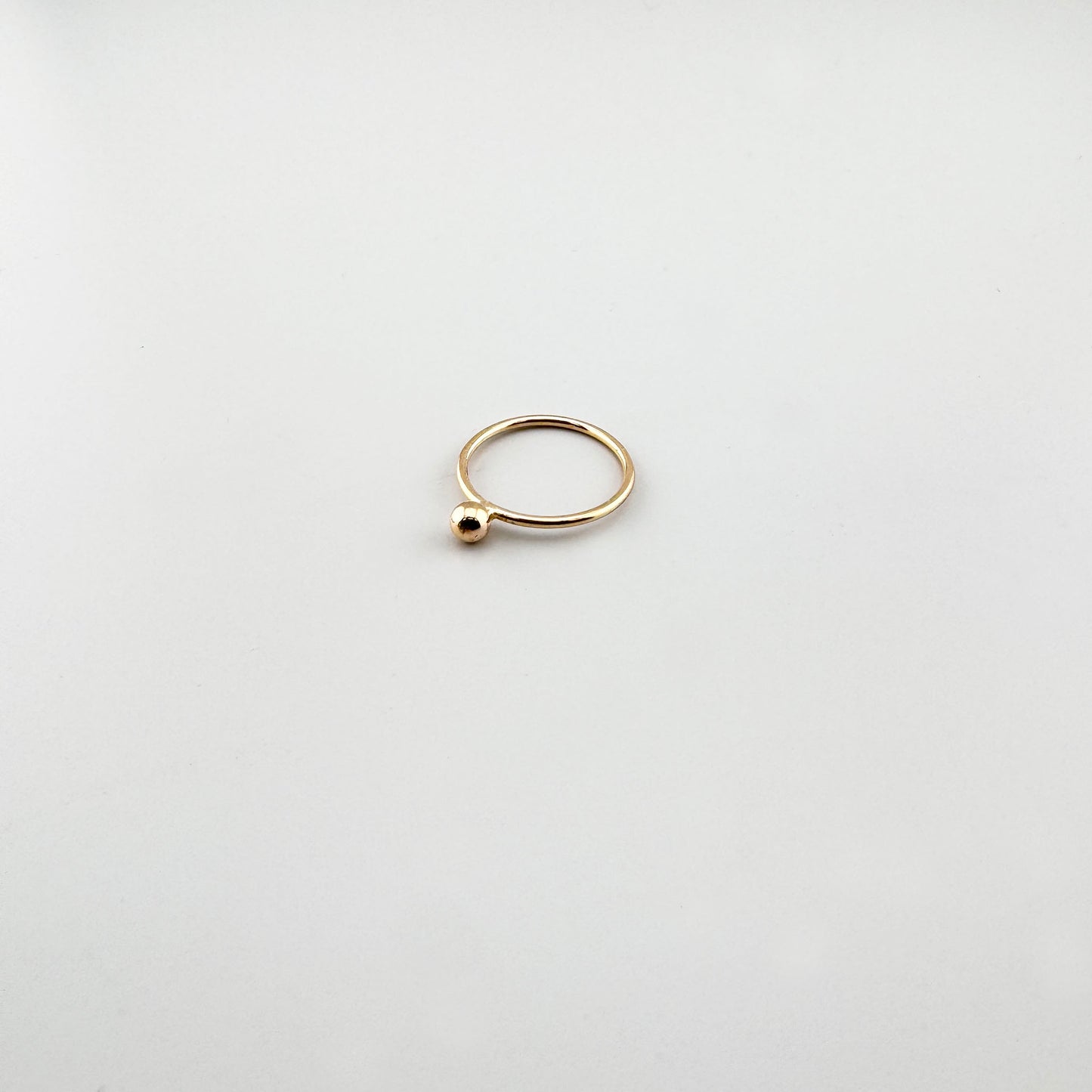 Anillo dorado LULU Copenhagen con pequeña esfera y diseño abierto minimalista