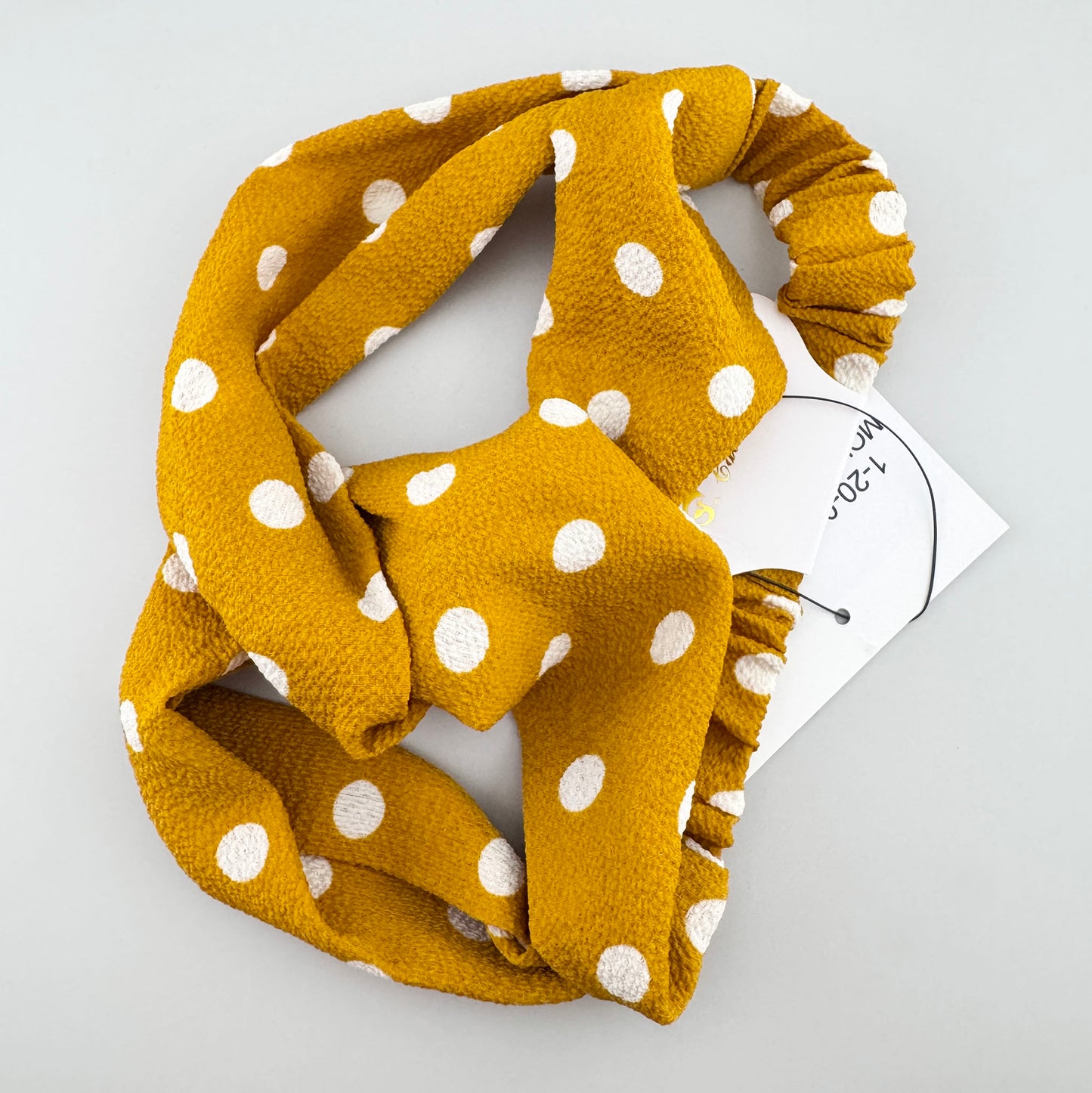 Mustard polka dot headband IRL with a soft twist front and elastic back