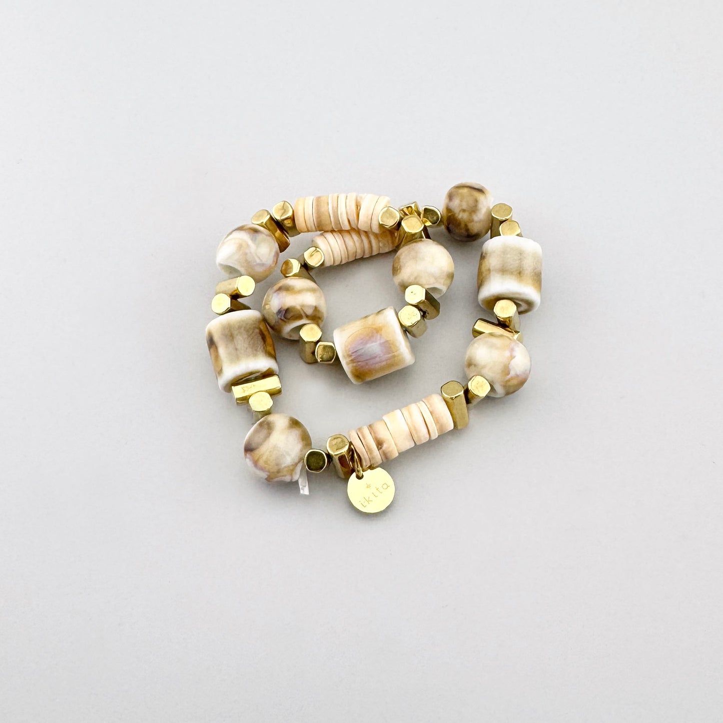 Bracelet en céramique beige avec détails géométriques dorés, style artisanal de la marque Ikita.