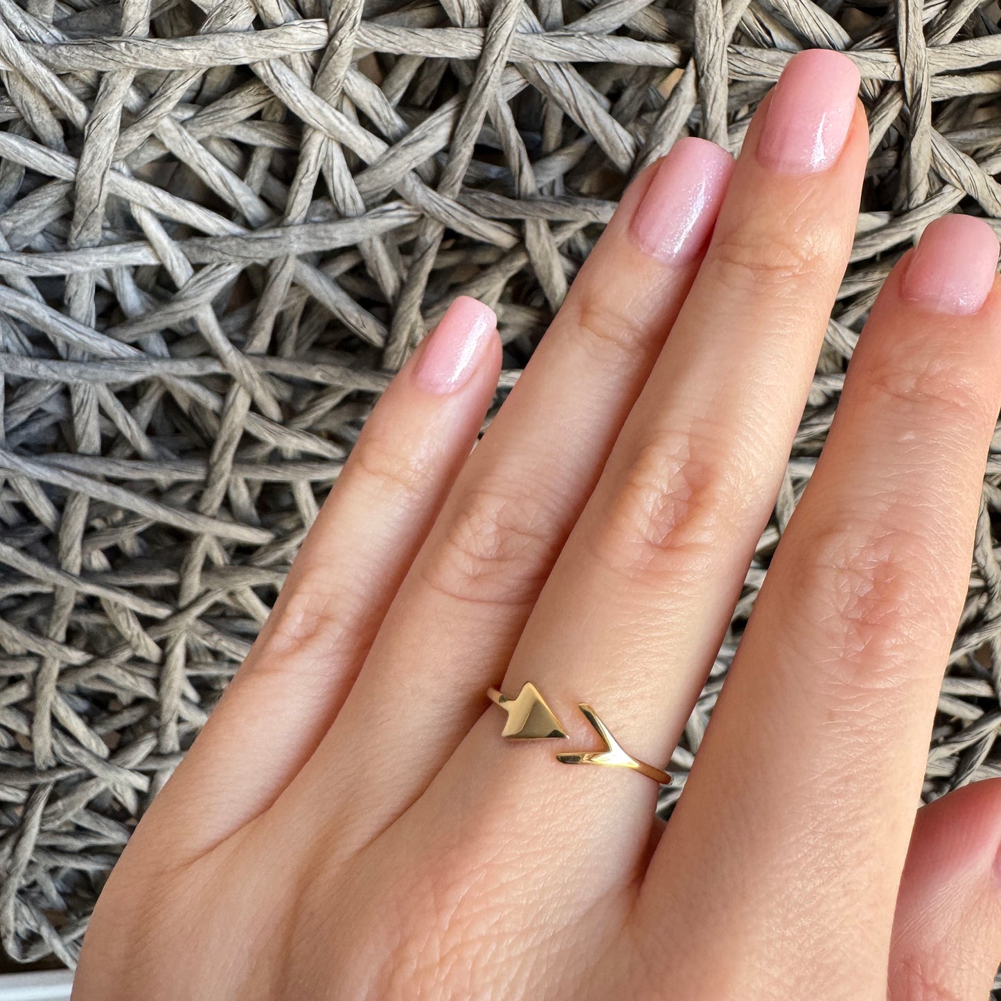 Gold open IRL ring with arrow and triangle motif worn with stacked jewelry