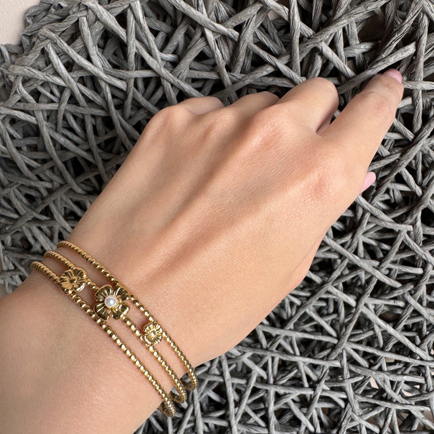 Elegant gold cuff bracelet with floral and pearl details worn on wrist