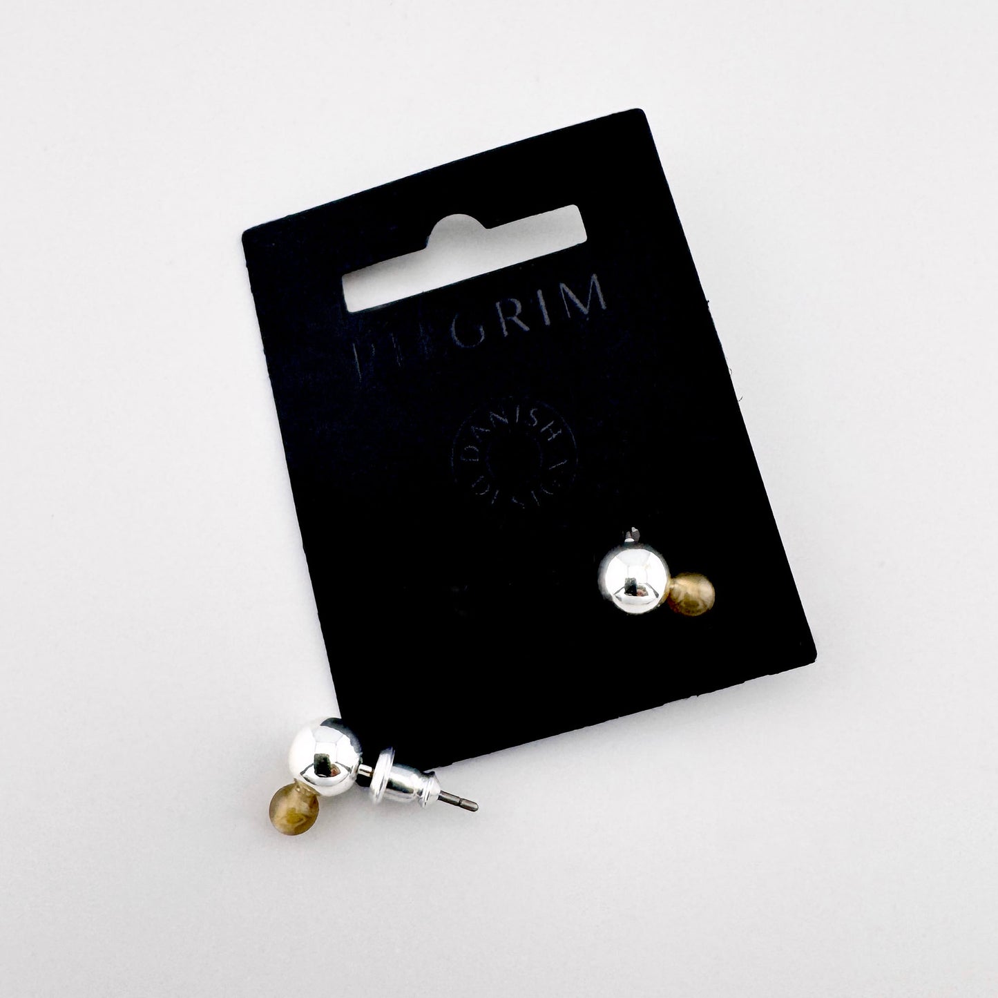 Silver and amber double-sided stud earrings on Pilgrim branded card