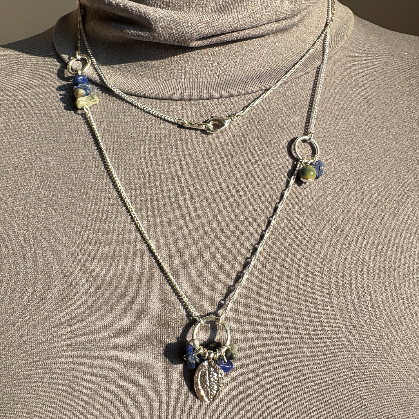 Pilgrim necklace with leaf charm and cobalt blue stones layered on mannequin