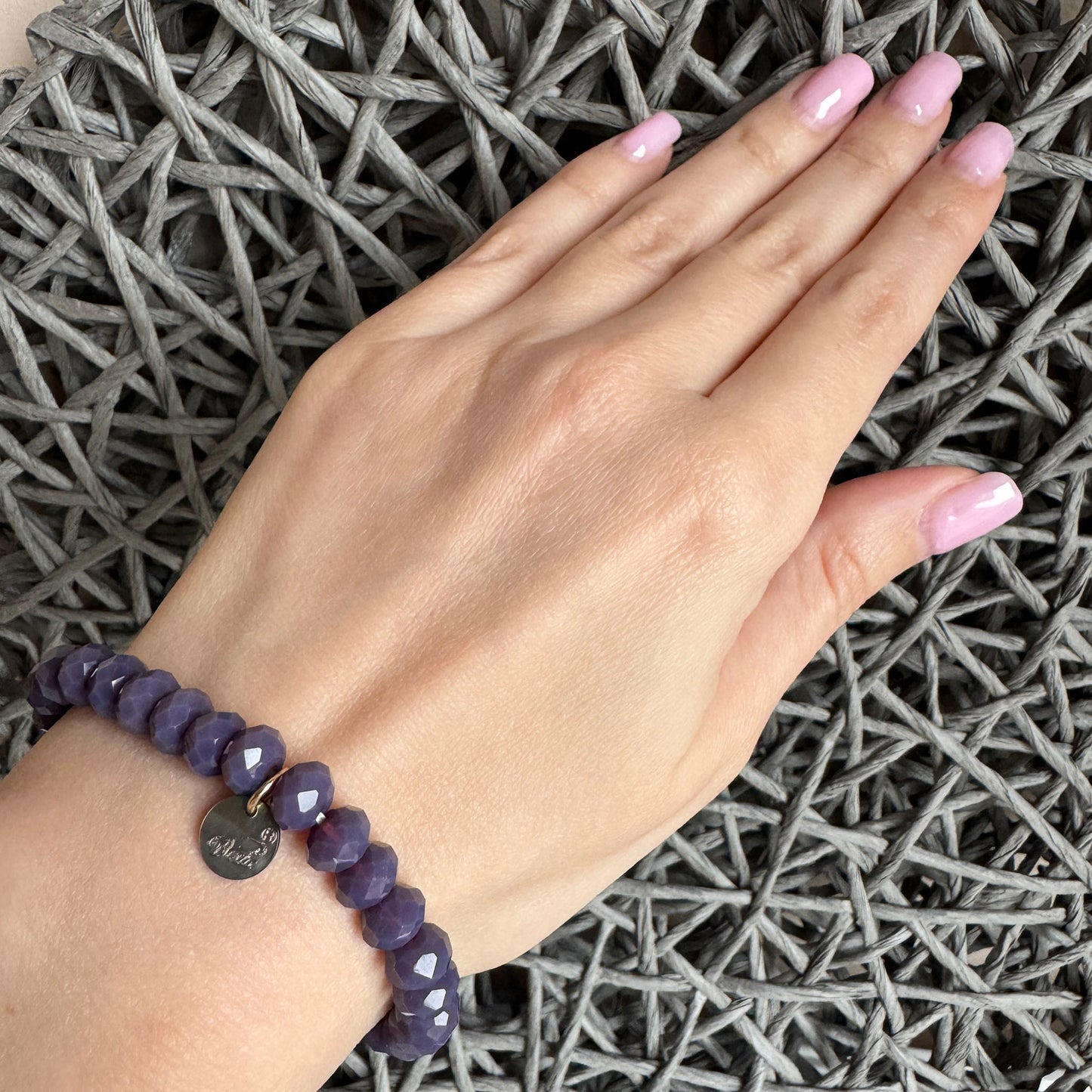 Elastic bracelet with faceted purple glass beads on wrist