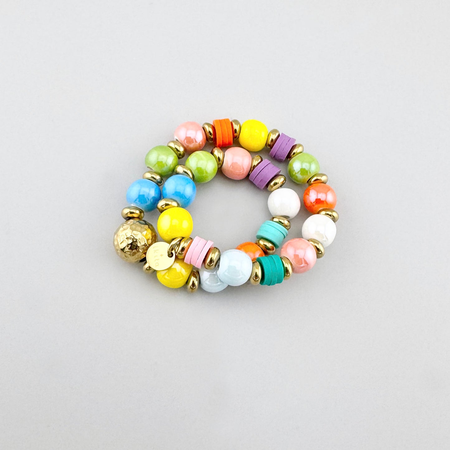 Pulsera bohemia con cuentas cerámicas de colores y bola dorada central, diseño de Ikita.